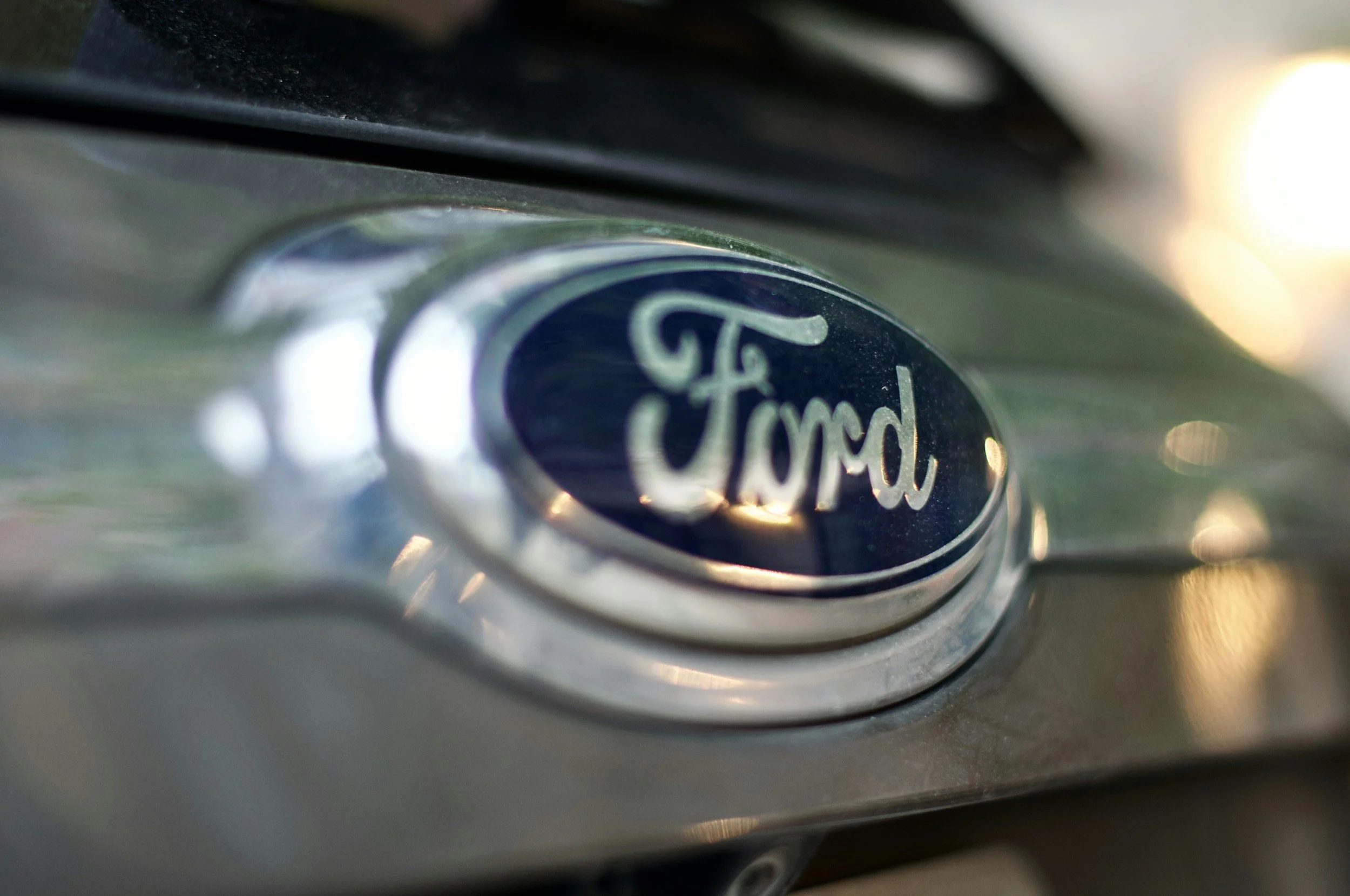 Close-up of a Ford logo on a car's front grille.