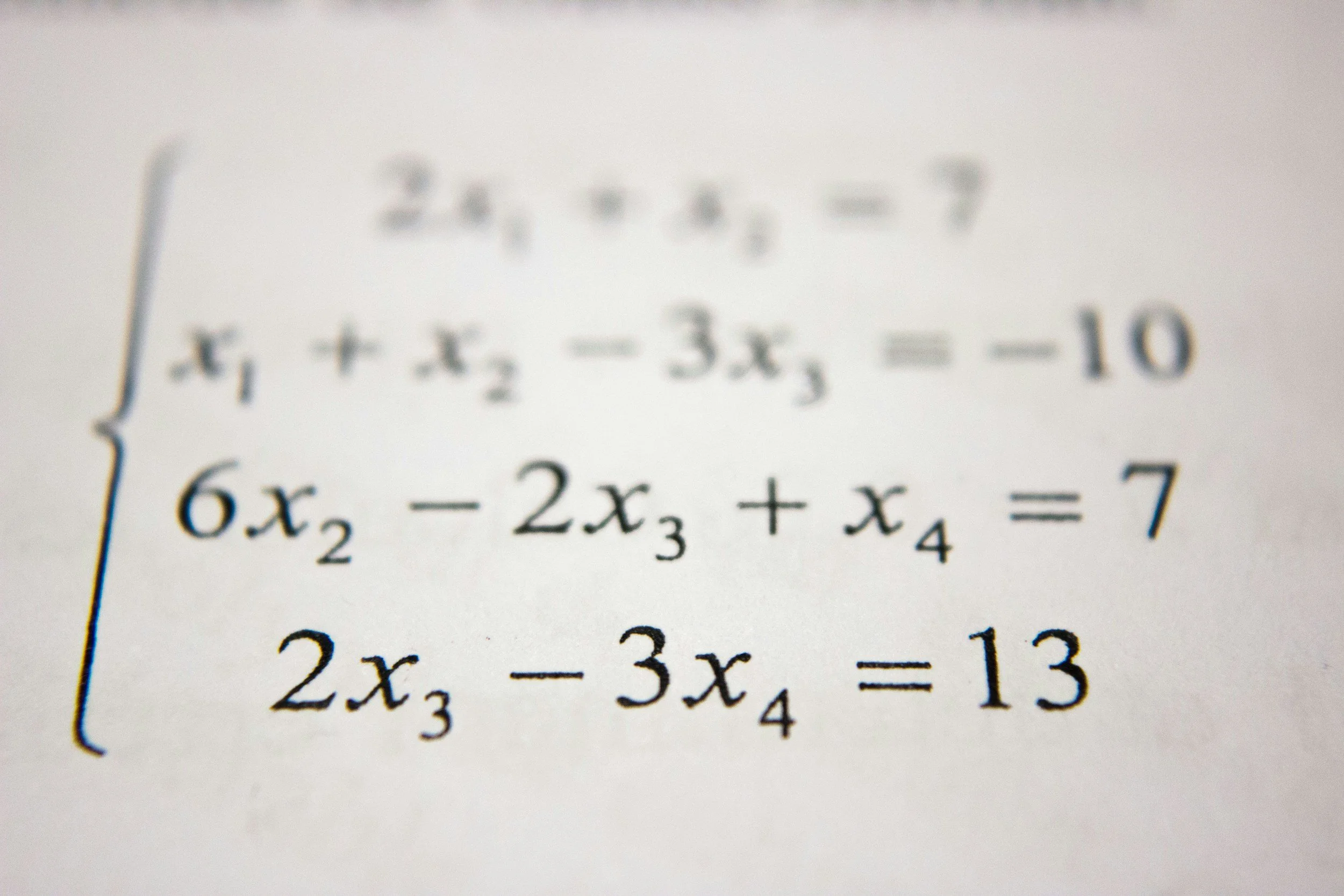 Close-up of a system of equations written on paper, including variables x1, x2, x3, and x4.