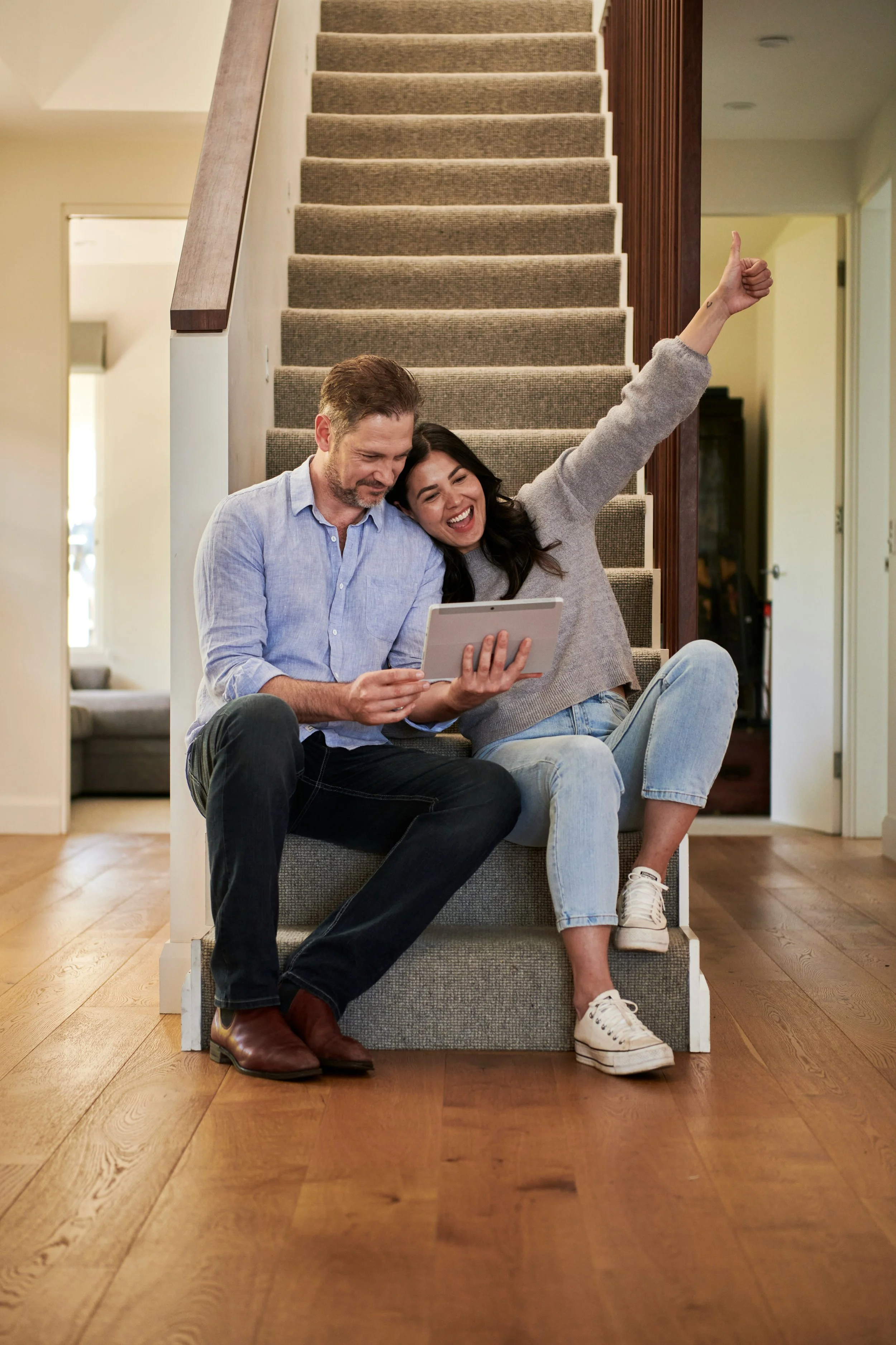 A man and a woman sitting on a staircase, discussing potential home improvement projects.