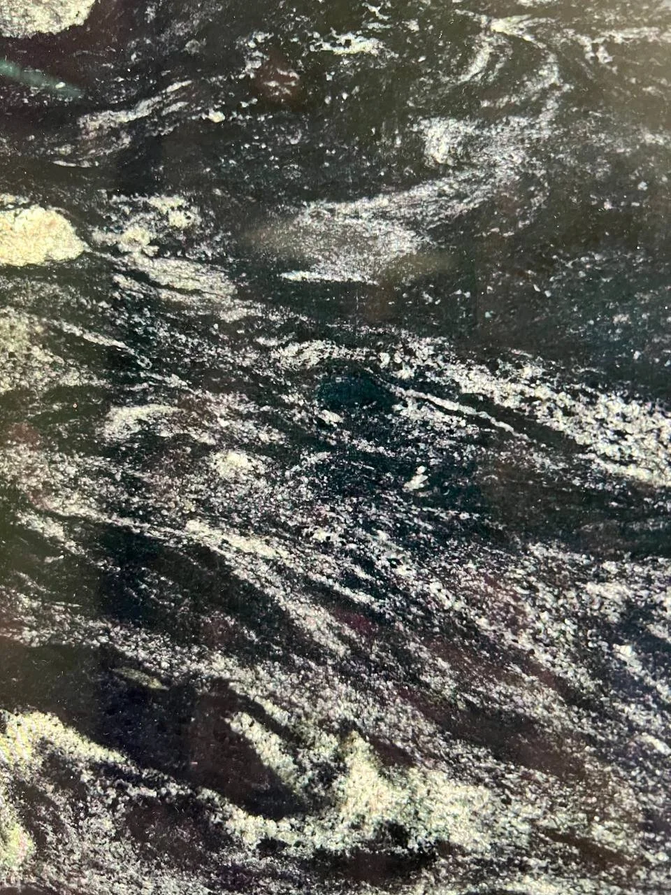 Arabian Night Granite. A Close-up of a textured stone surface with swirling dark and light patterns.
