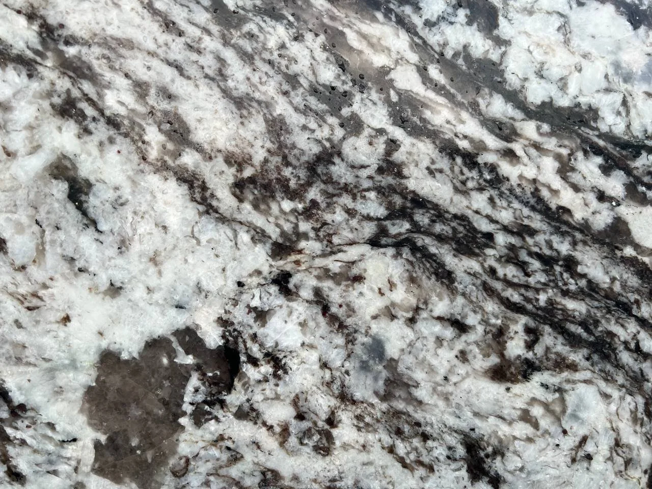 Azul Celeste Granite. A Close-up of a textured stone surface with brown and white swirls and patterns.