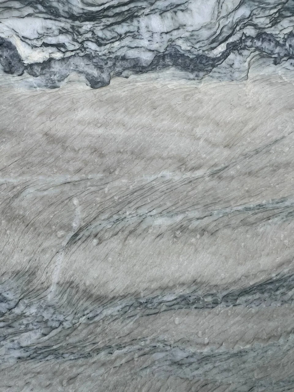 Close-up view of a textured marble surface with gray and white swirls.