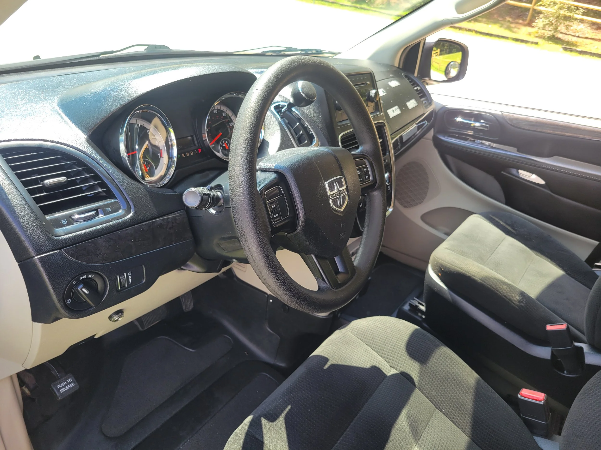 Interior of a car showing the dashboard, steering wheel, and front seats, with sunlight coming through the windshield.