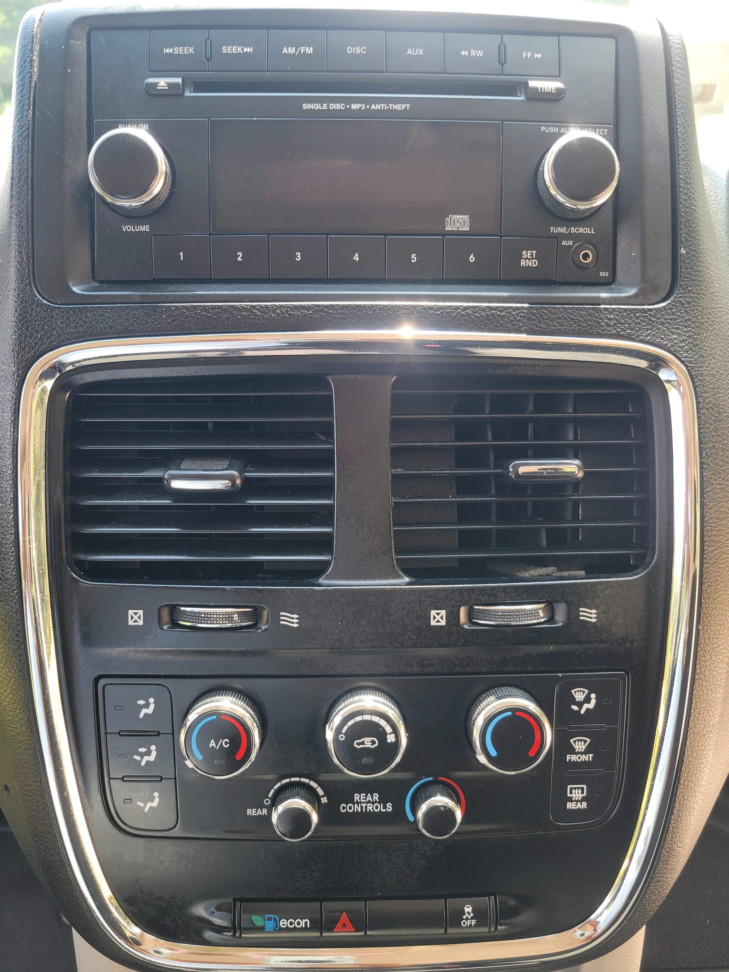 Car air conditioning and heating control panel with various dials, buttons, and vents.