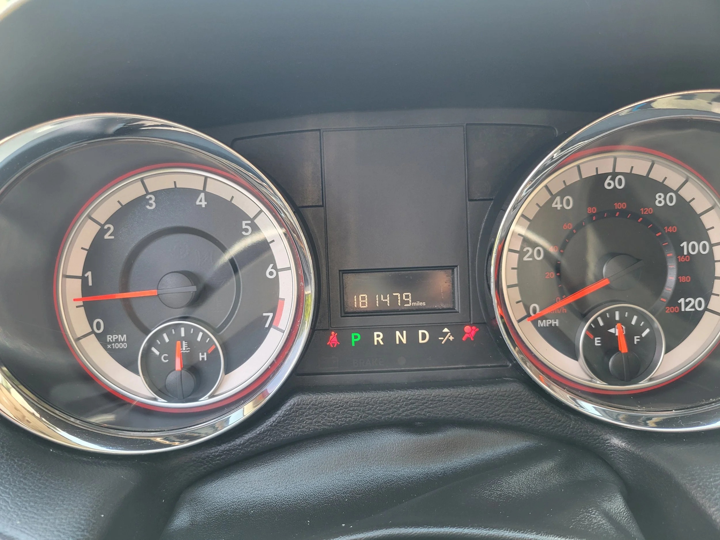 A car dashboard showing speedometer, tachometer, fuel gauge, temperature gauge, digital odometer reading 181479 miles, and gear display in park.