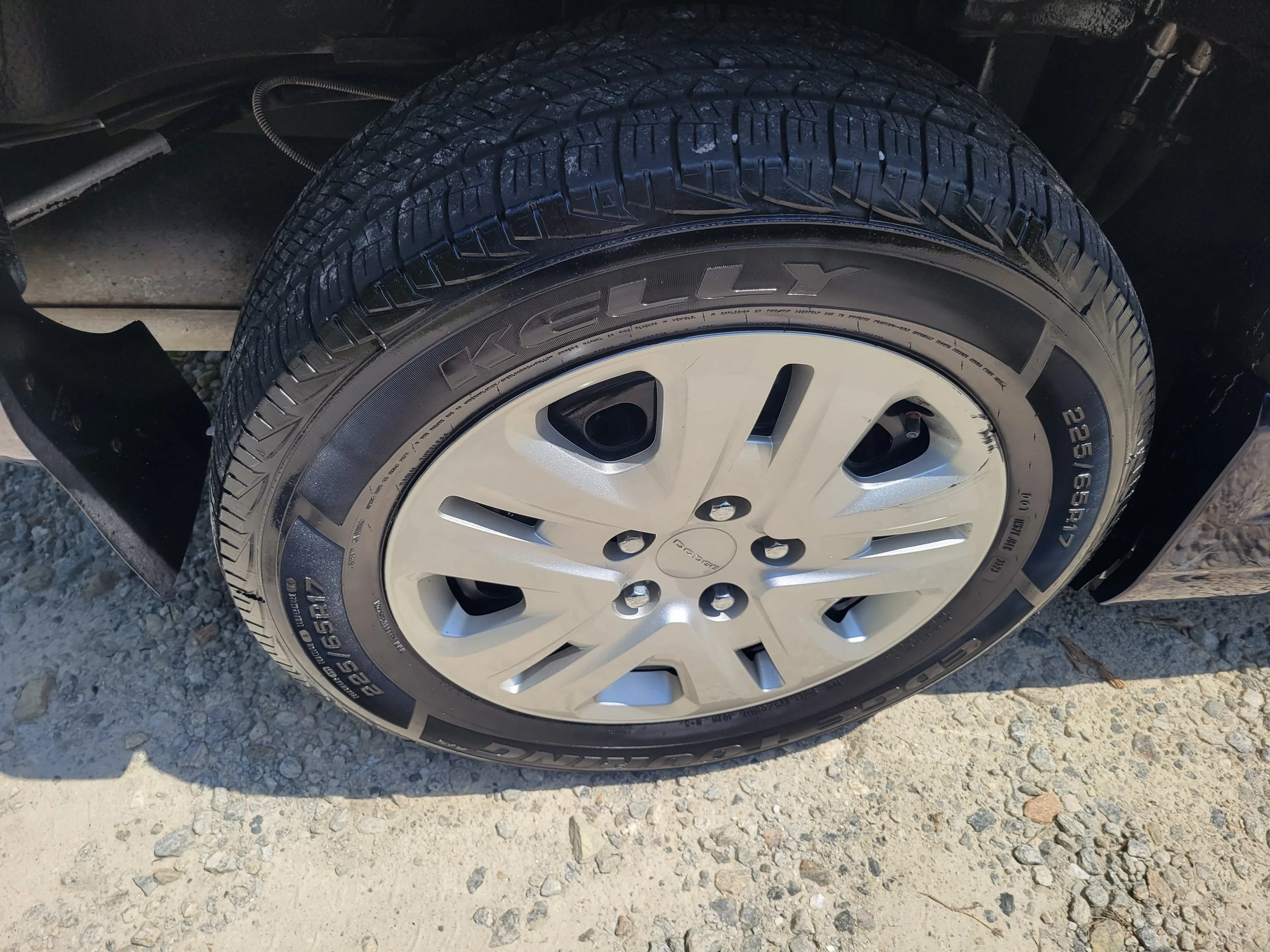 Close-up of a vehicle tire with the brand name 'Kleber', mounted on a silver alloy wheel, parked on a gravel surface.