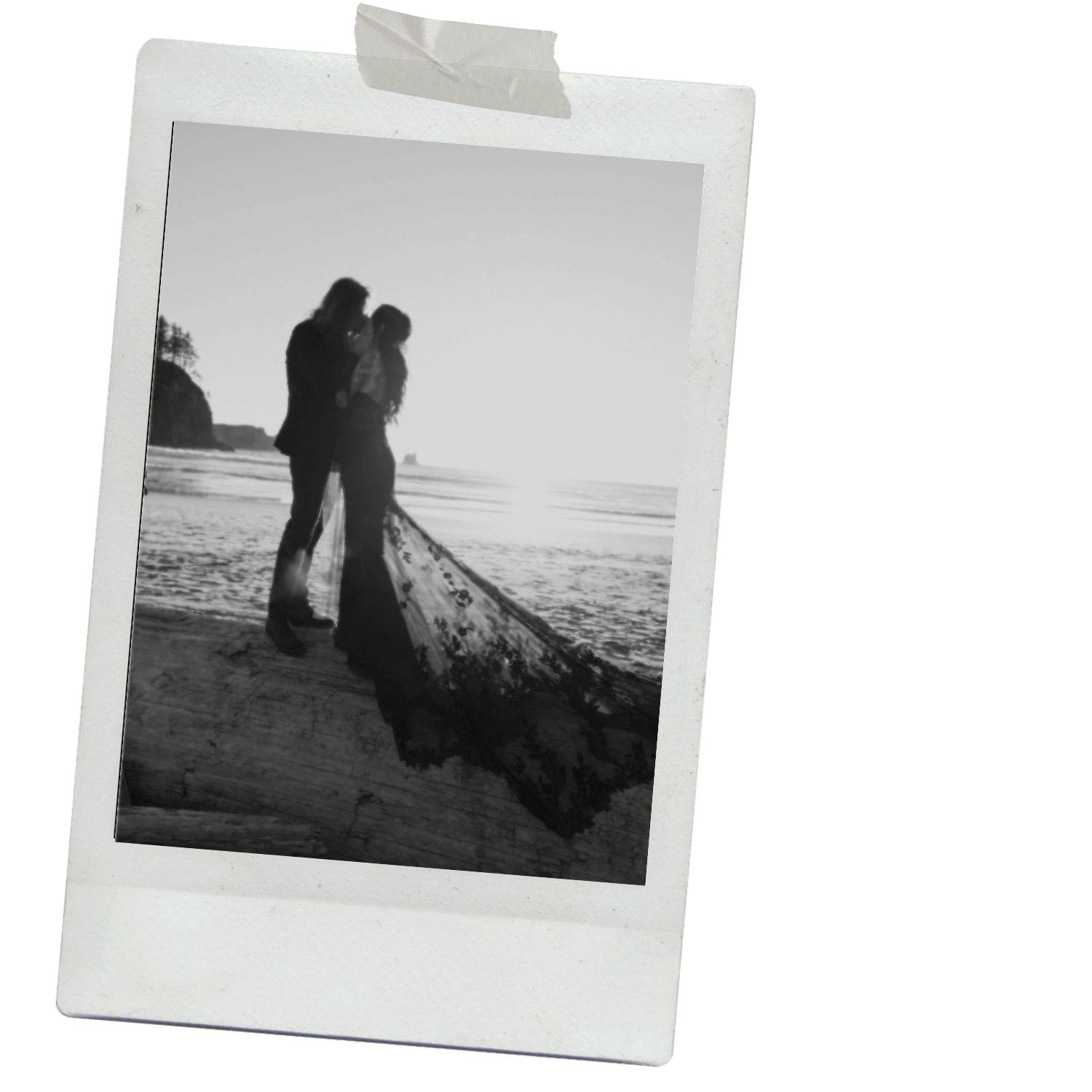 Silhouette of a couple on a beach at sunset, with the woman’s long lace dress flowing on the sand.