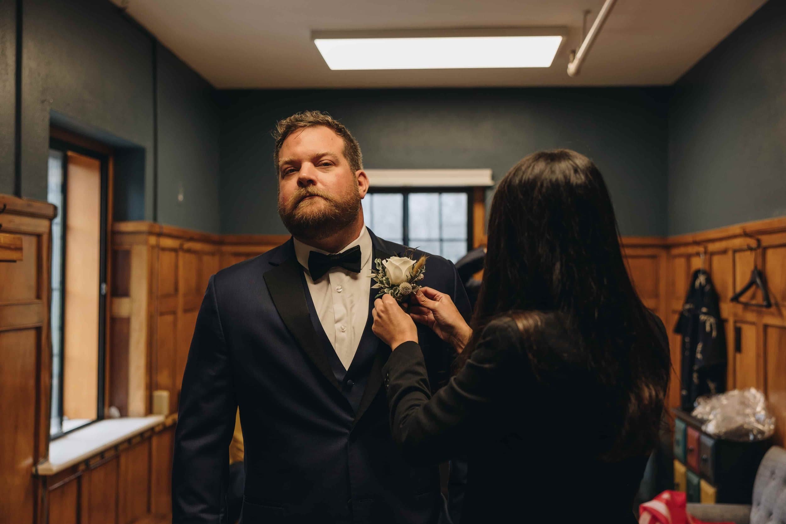 Wedding planner helping groom with boutonniere