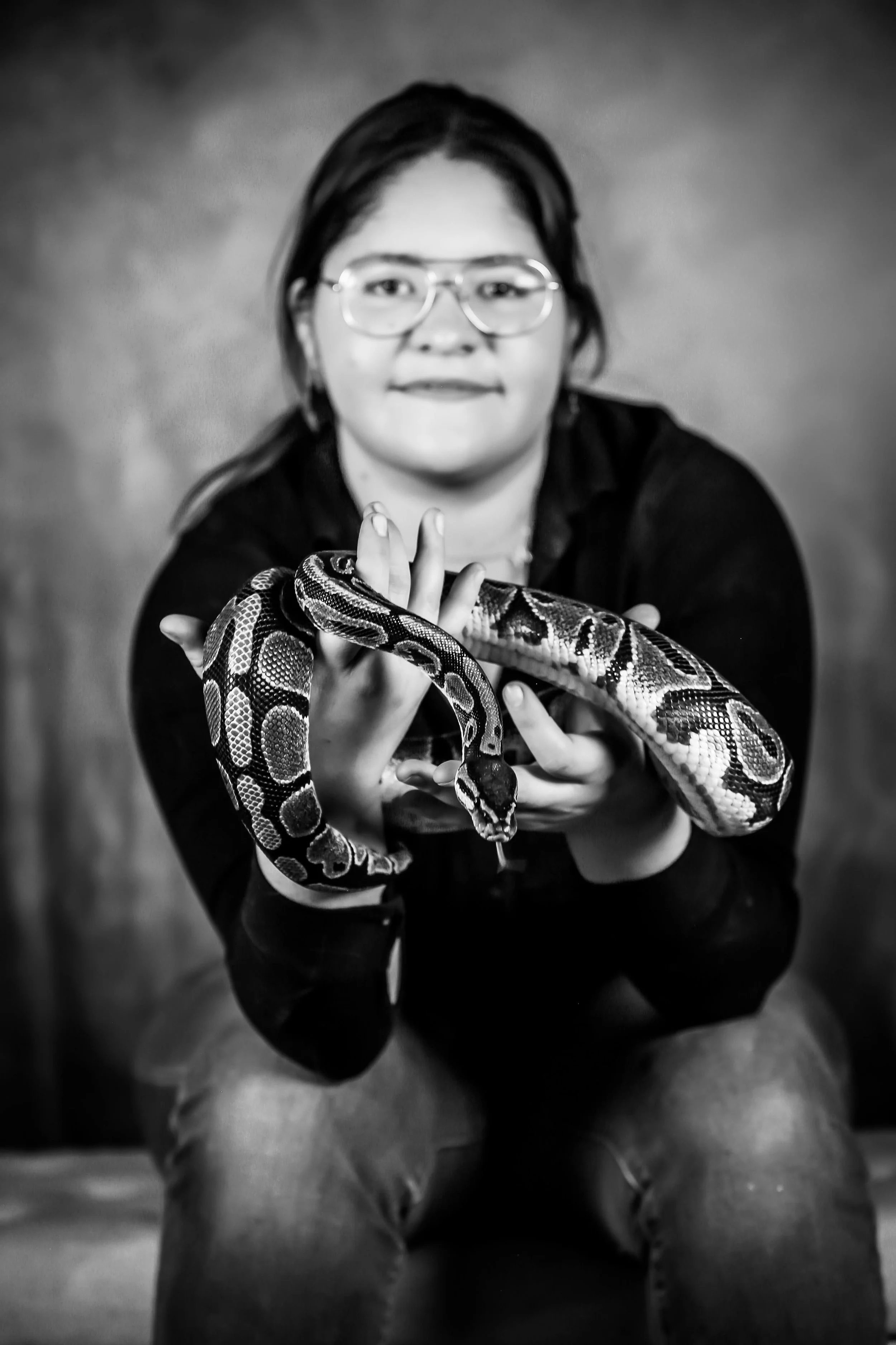 A woman with glasses holding a snake.