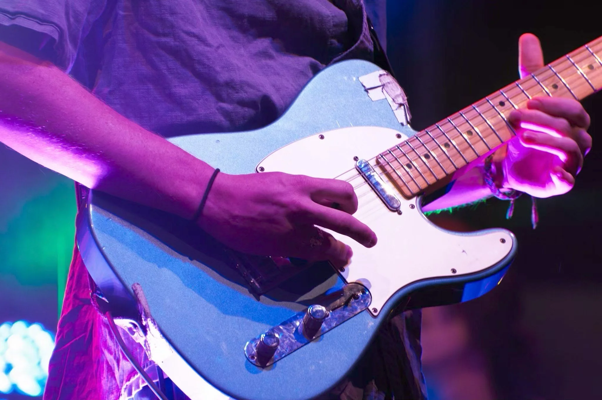 Ryan playing an electric guitar under colorful stage lighting.