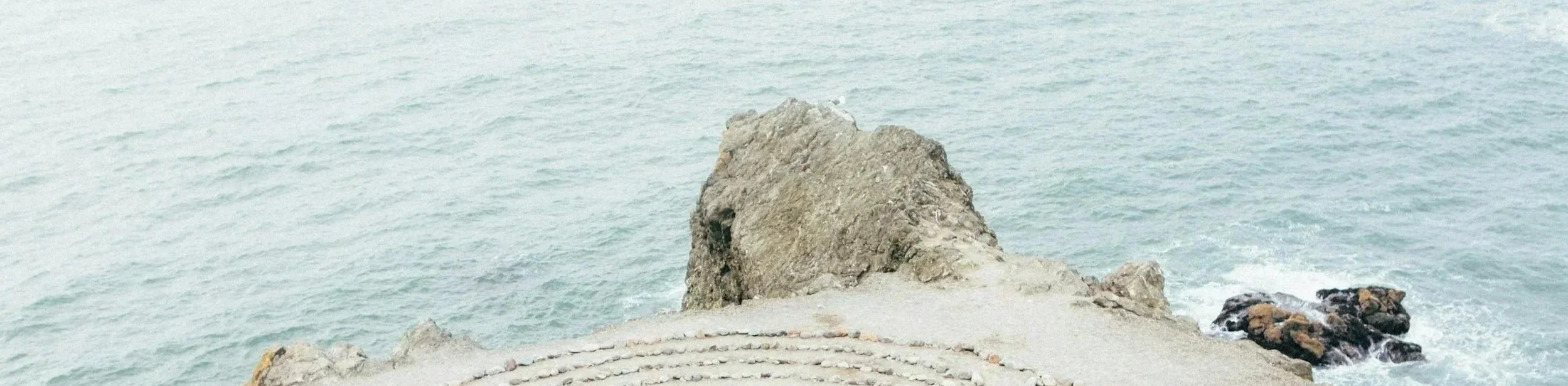 View of rocky shoreline with the ocean in the background, taken from a vantage point on the coast.