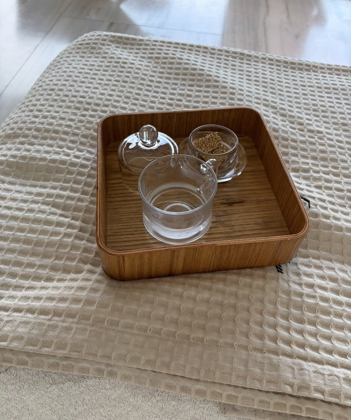 Glass cups on a wooden tray resting on soft linen