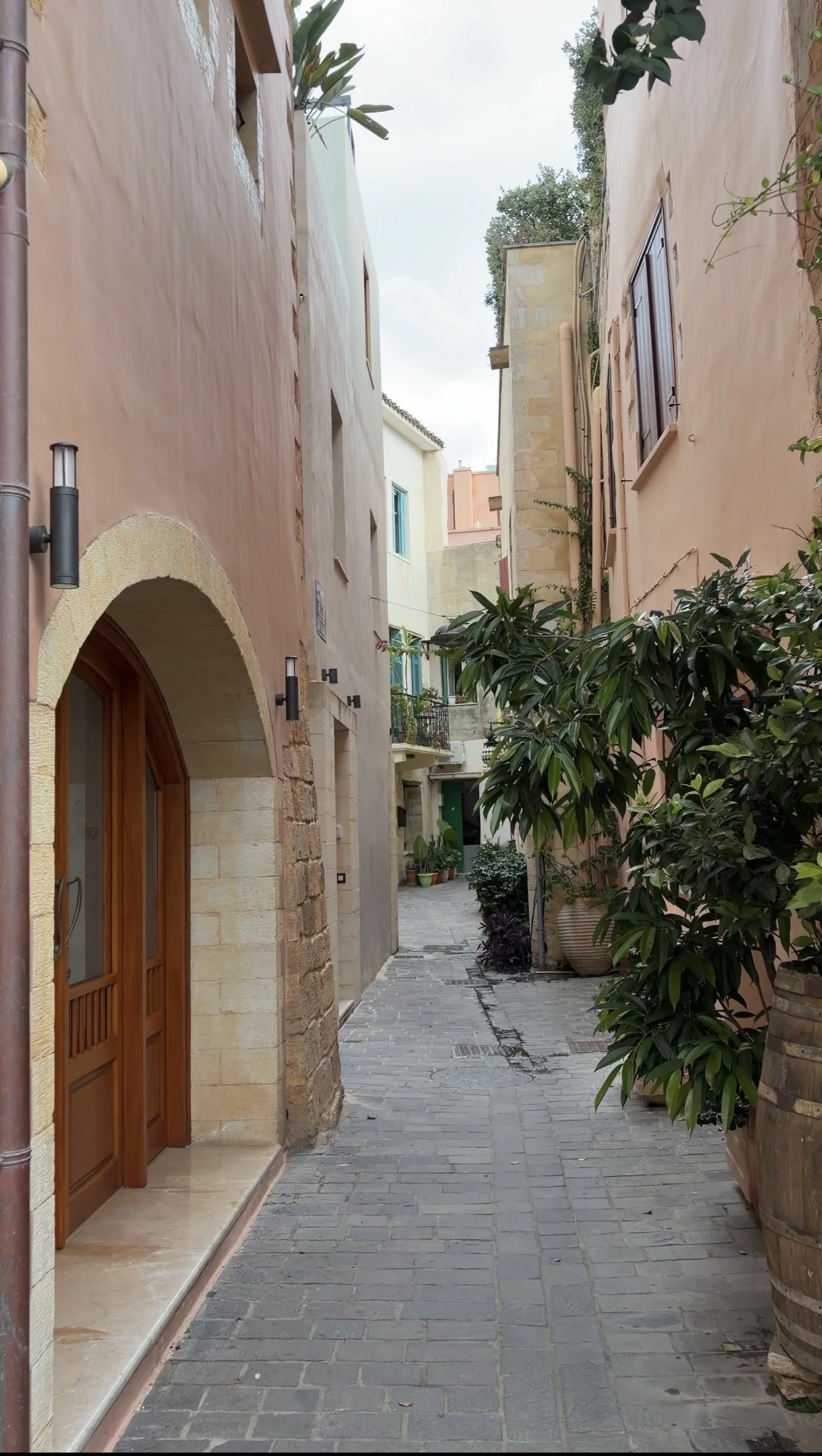 A warm pink alley with an arched wooden doorway
