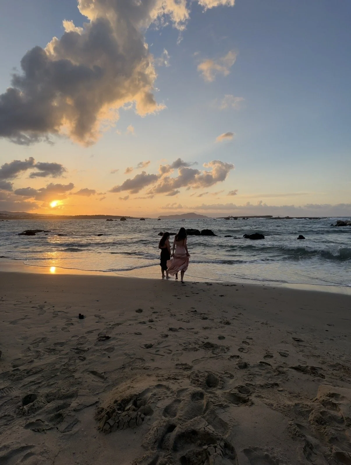 Two women walking along the beach at sunset on a wellness retreat