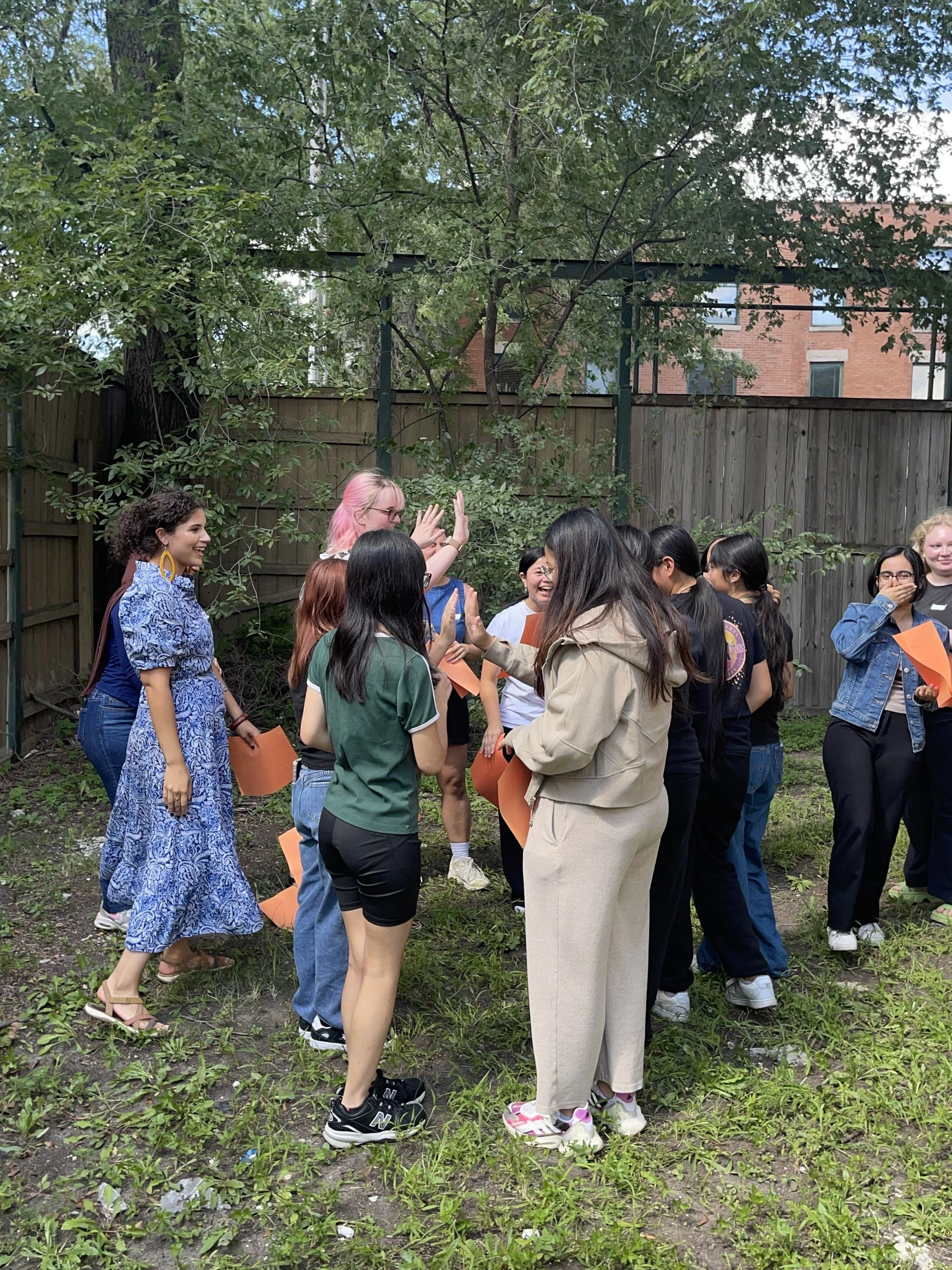 Group of women and girls in a backyard, engaging in a high-five or celebration.