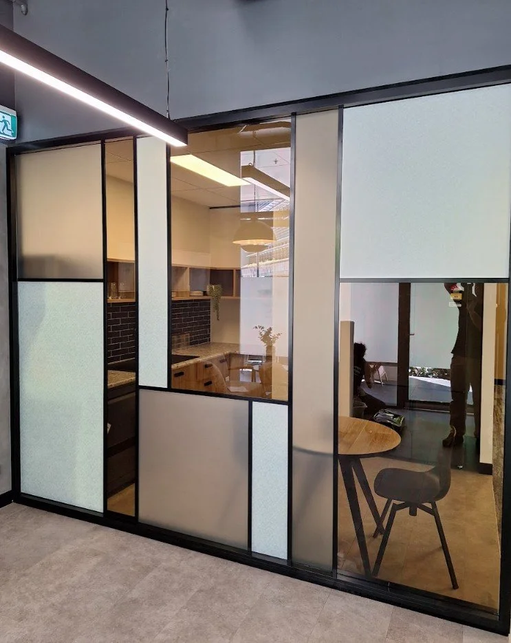 A geometric glass partition design using a mix of tinted and frosted film panels in different shades for a contemporary look.