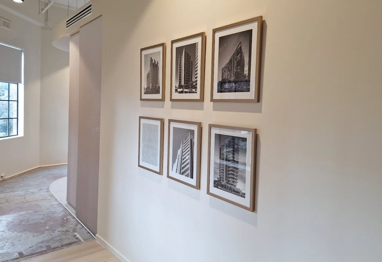 A precise grid of six framed black and white photographic prints installed in a Brisbane office hallway.