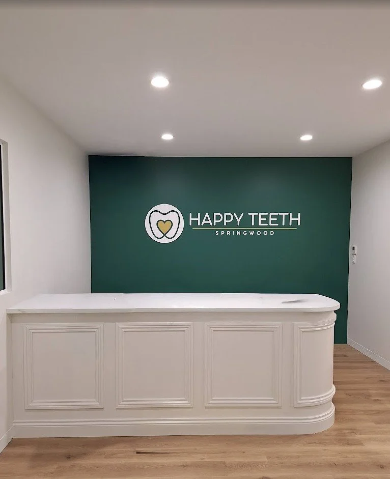 Backlit 3D acrylic corporate logo sign for a dental clinic reception desk, featuring green branding on a white wall in Brisbane.