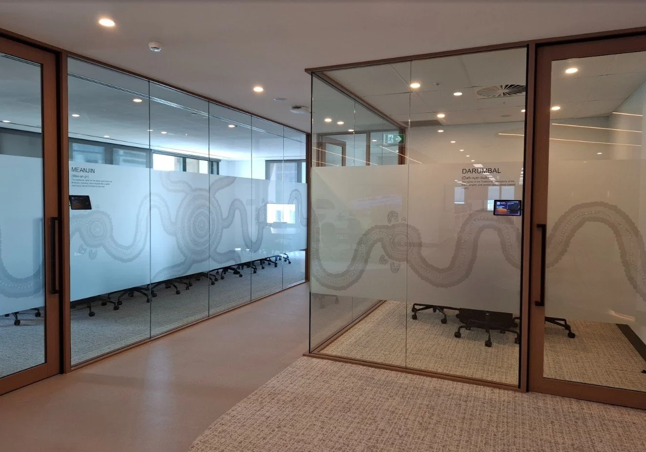 A hallway view of office glass doors featuring a custom frosted film with a continuous, flowing line art pattern.