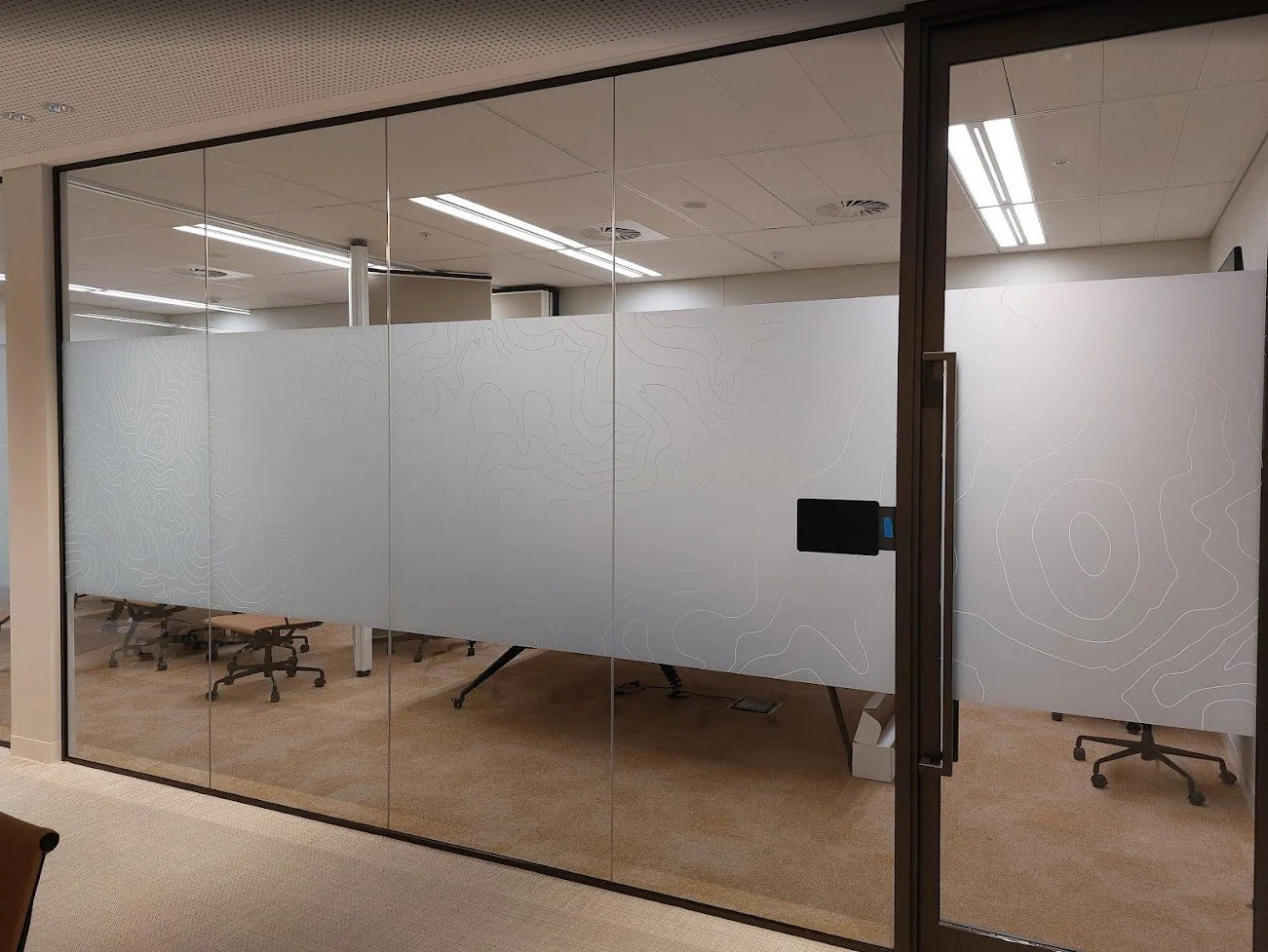 Bespoke frosted glazing film for office privacy, featuring a custom-printed decorative geometric design.