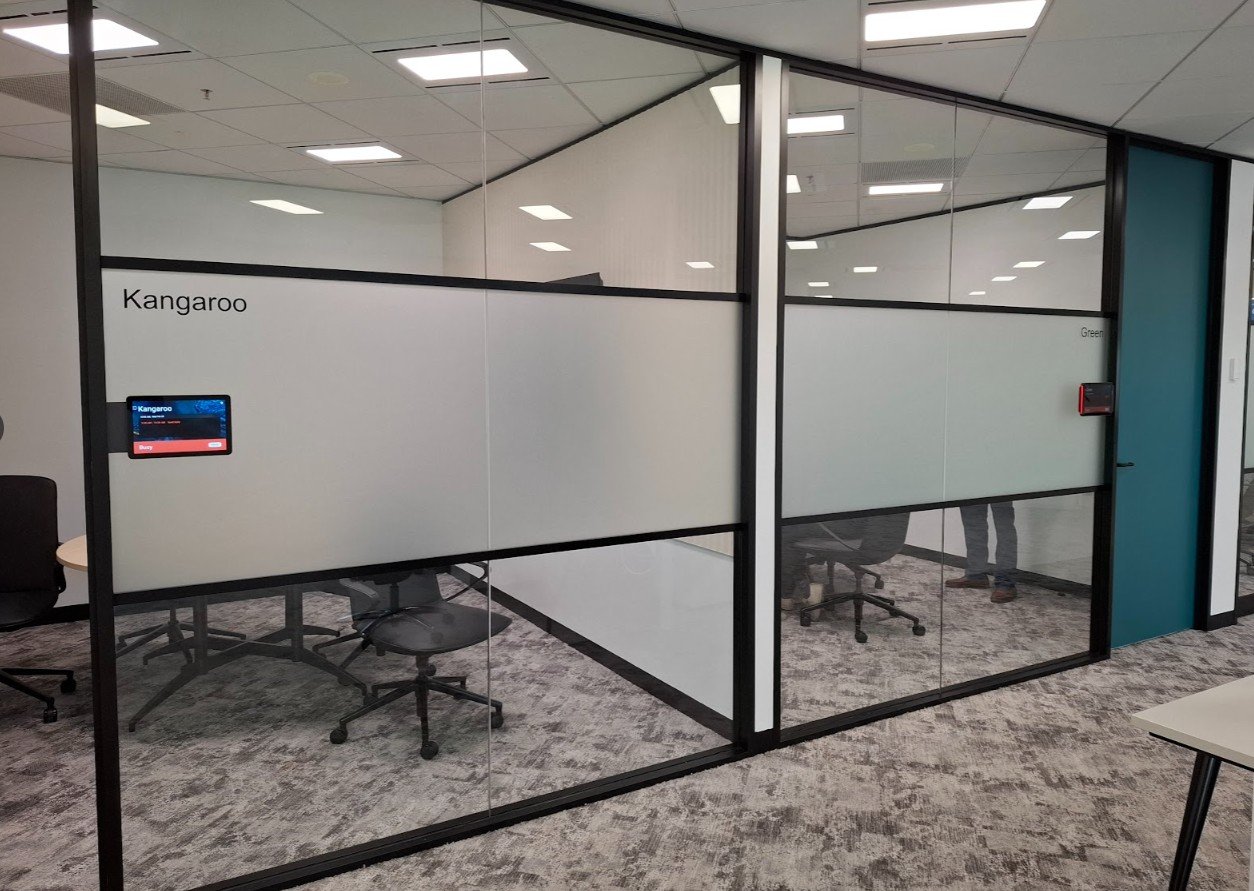 Modern office glass walls with a wide, frosted privacy band at eye level, including black frames and room labels.