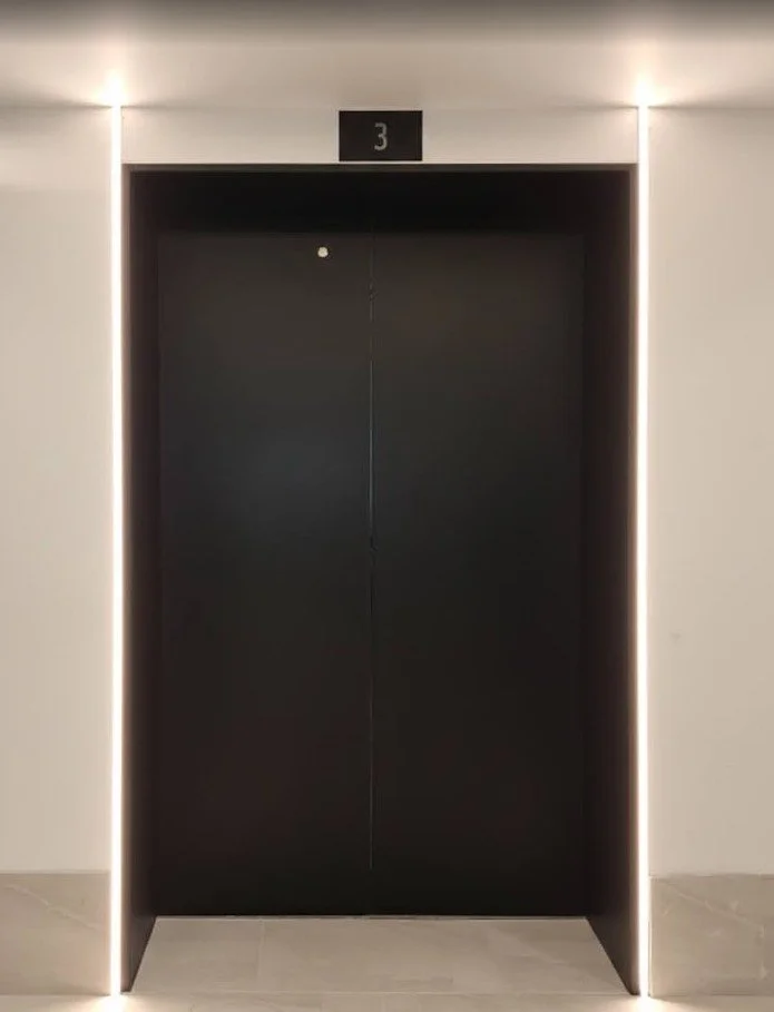Professional elevator interior featuring a 3M Di-Noc architectural vinyl wood-grain wrap installation in a Brisbane office building.