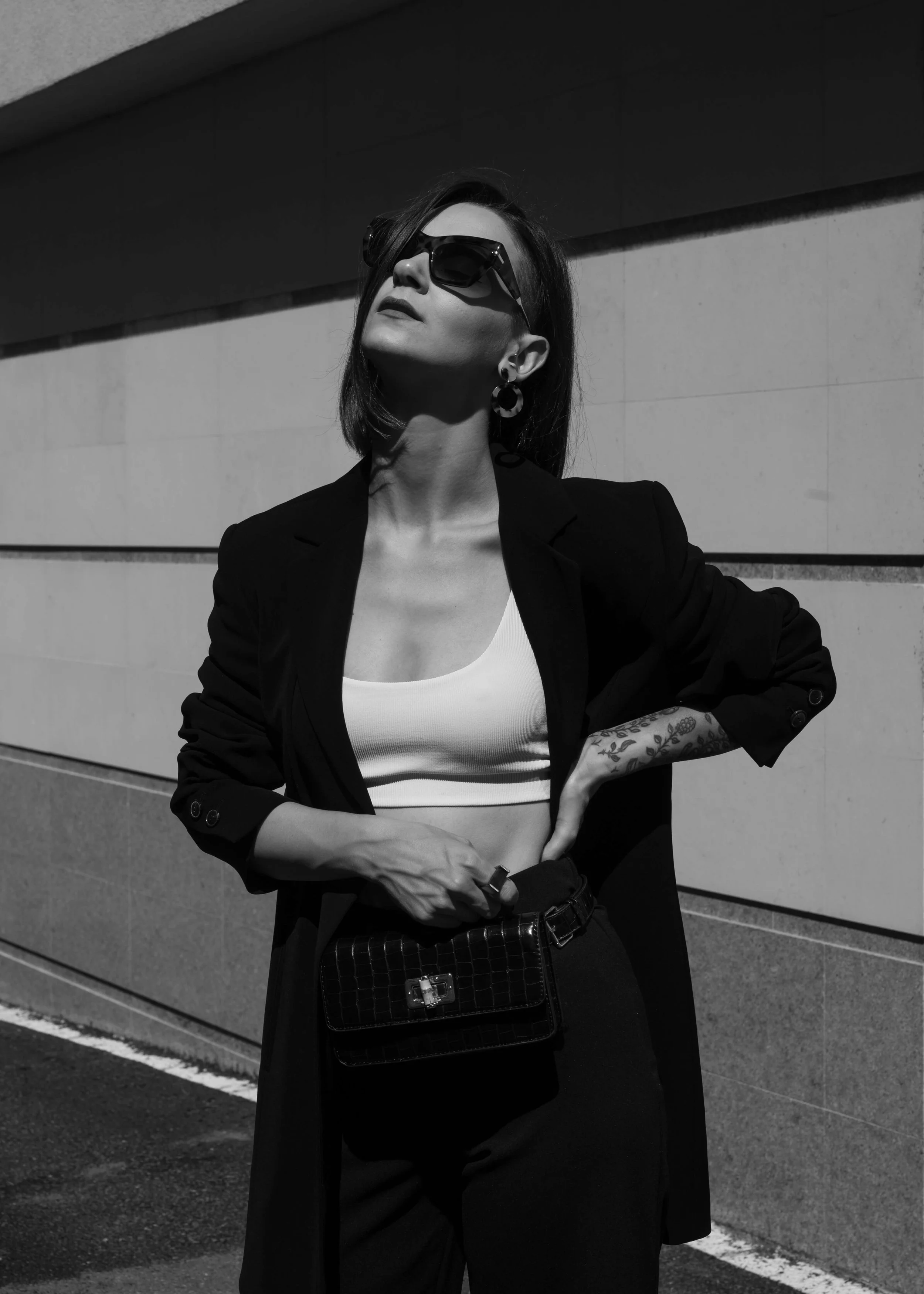 Black and White image of a well dressed woman wearing sunglasses with her head tilted towards the sky - Virginia Marinova Unsplash