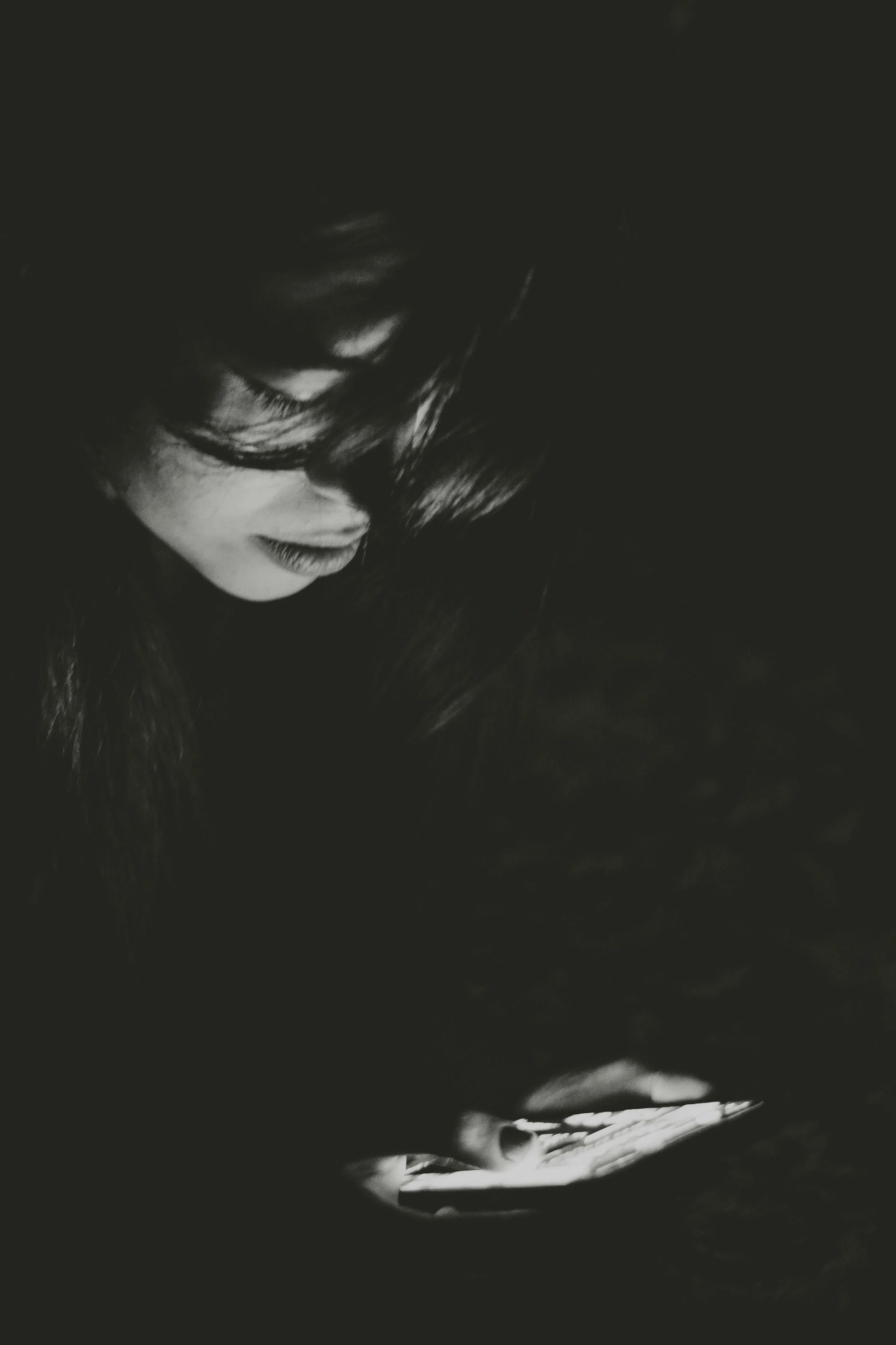Black and white image of a woman looking at a mobile phone - Negar Nikkhah Unsplash