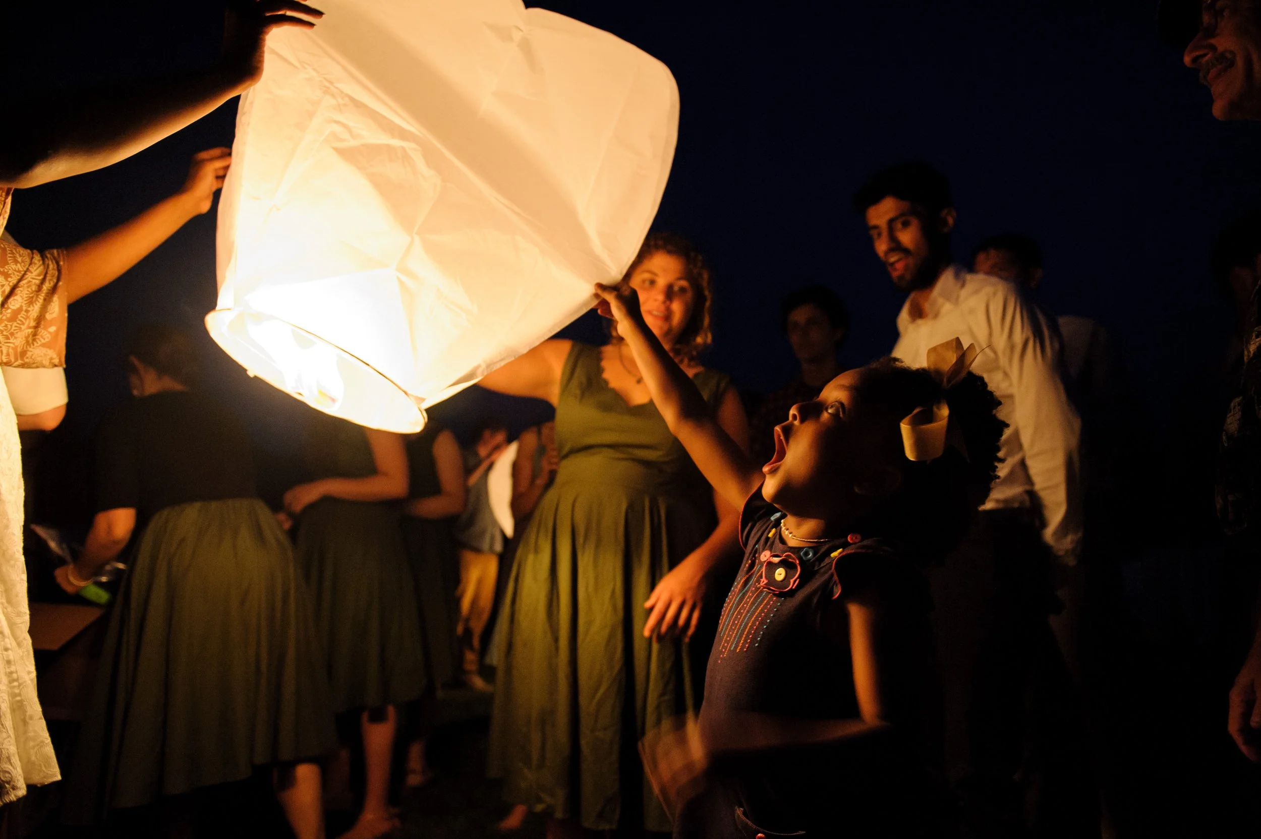 People releasing a sky lantern at night during a celebration.