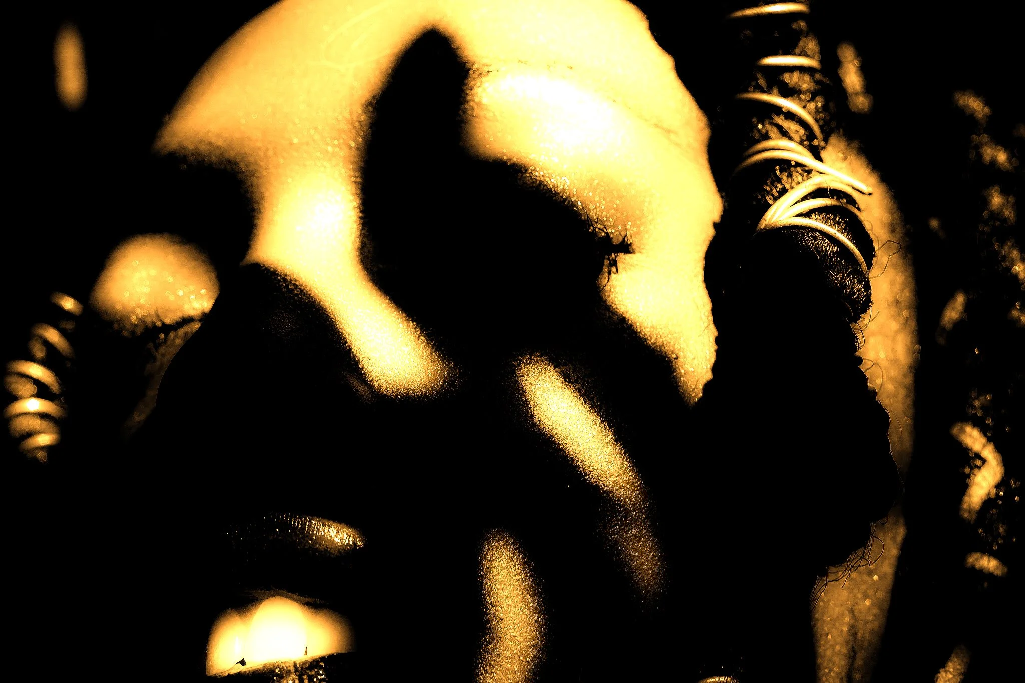 Close-up of a gold-colored Buddha statue with a hand touching the face, illuminated softly, in a dark background.