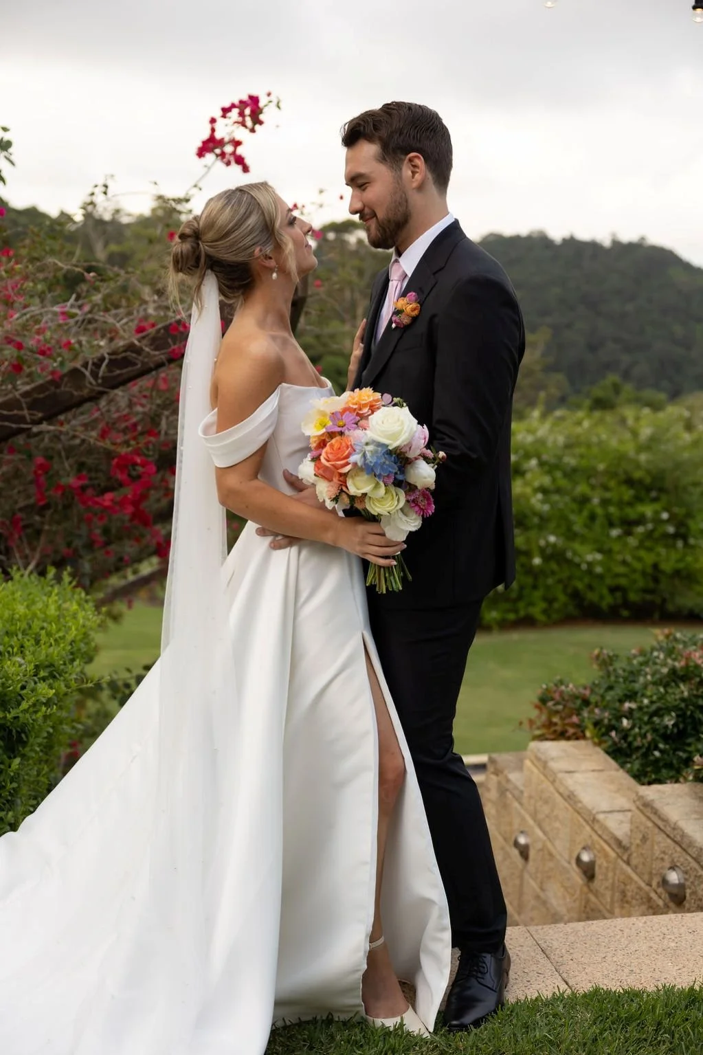 Maleny Manor Couple on Staircase with Flowers  in background & floral bouquet