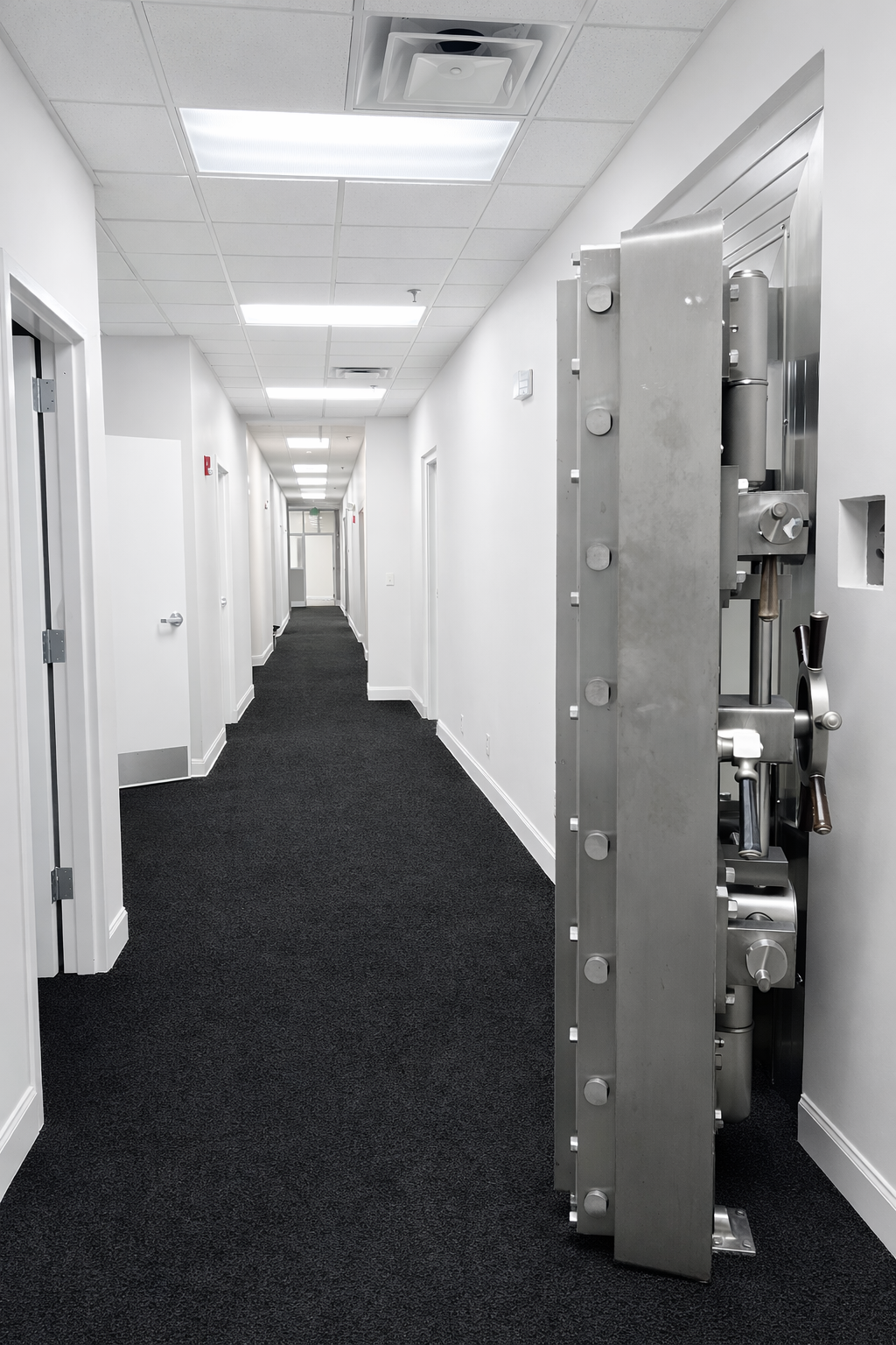 Empty hallway in a modern office building with a large metal safe partially visible on the right side.