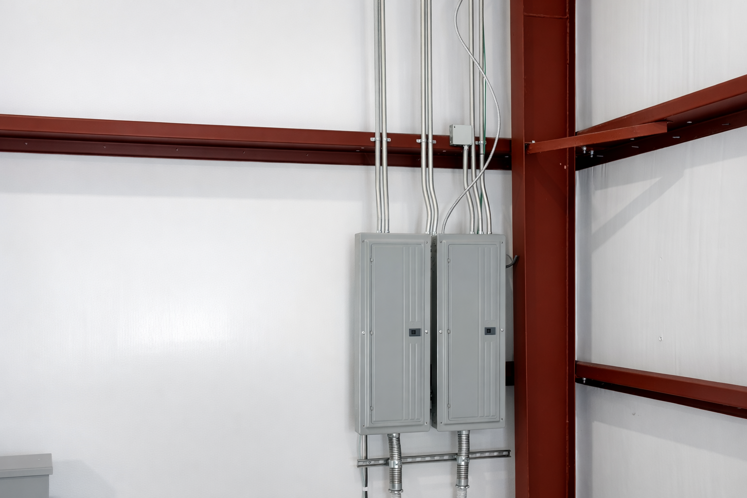 Electrical boxes mounted on a wall with red metal framing in the background.