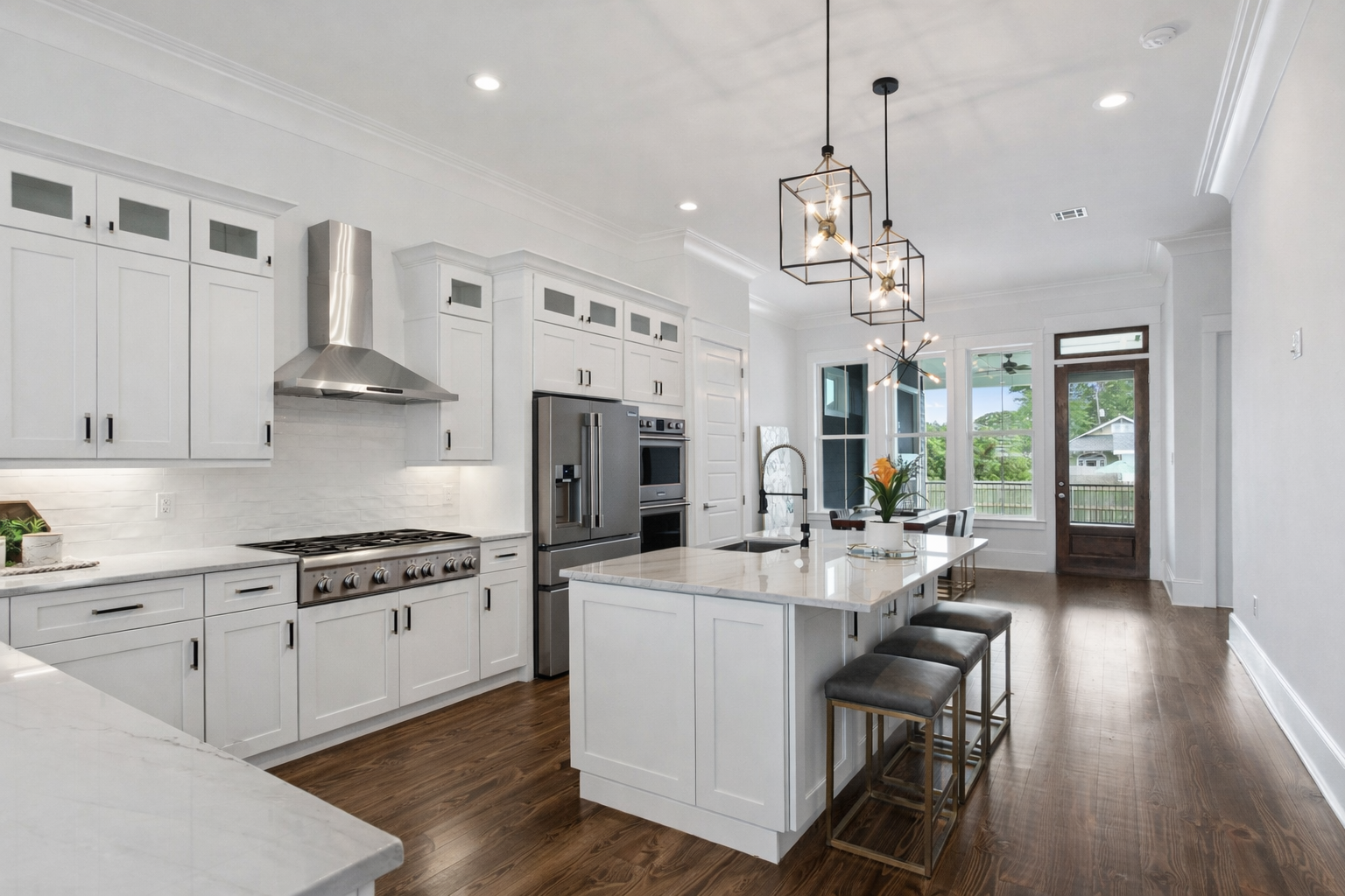 Modern kitchen with white cabinets, stainless steel appliances, a kitchen island, and large windows with a backyard view.