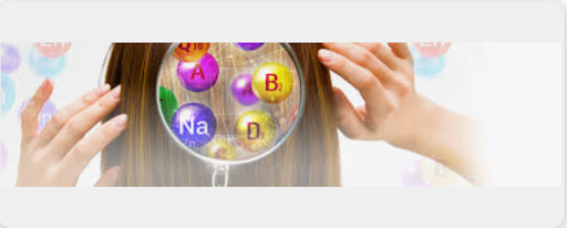 A person holding a petri dish with colorful chemical elements labeled A, B, Na, D, and E.