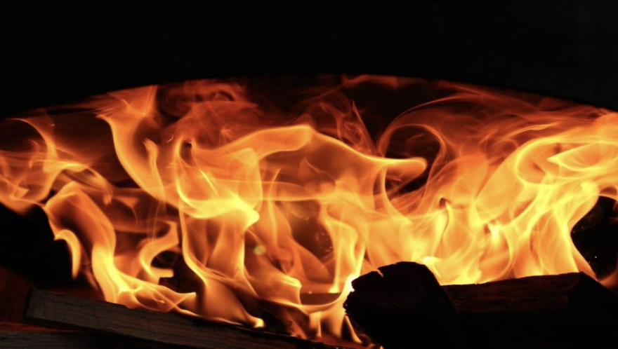 Close-up of bright orange flames with a piece of wood at the bottom.
