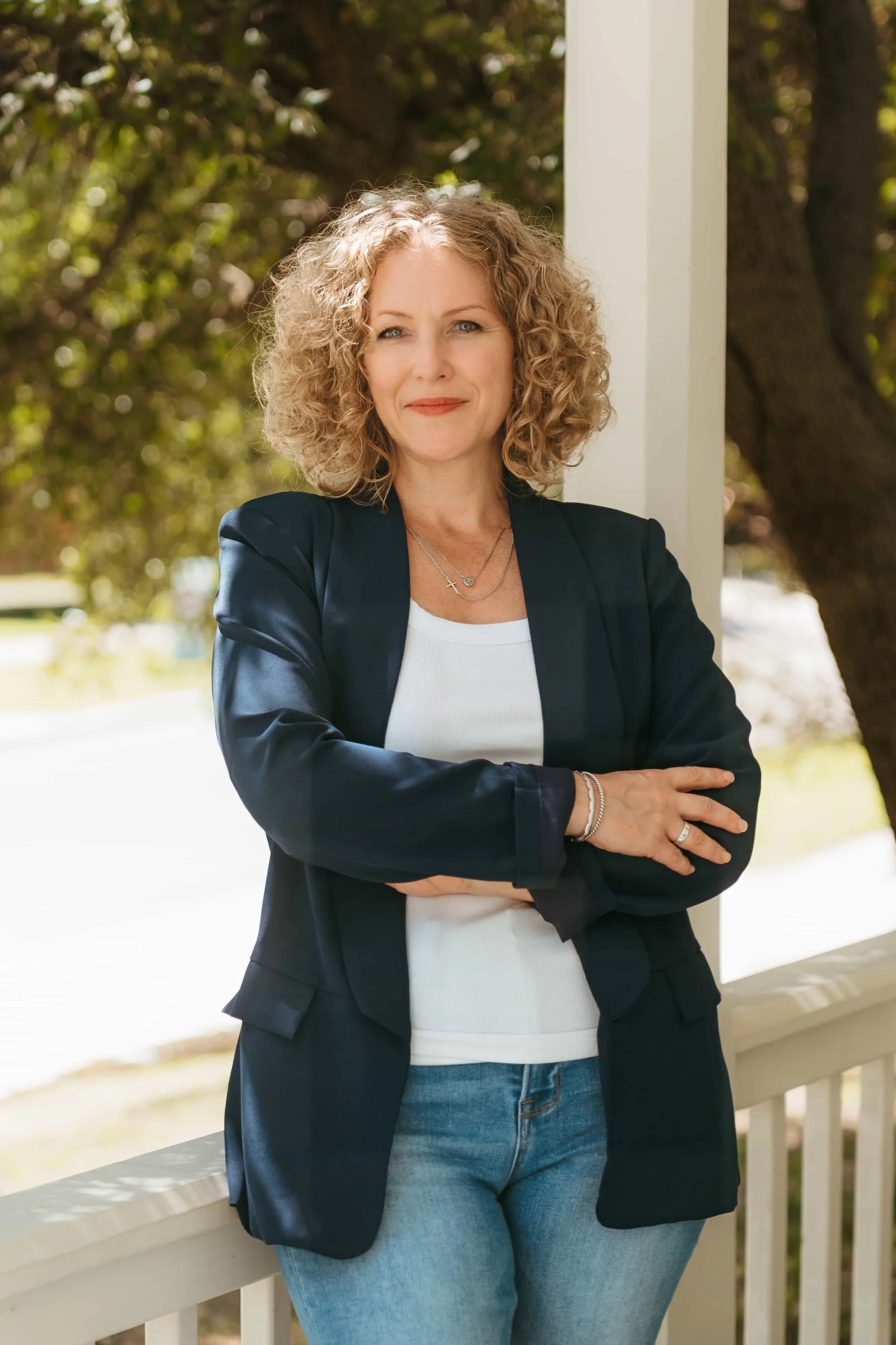 Maggie Roney standing on a porch with a tree in the background