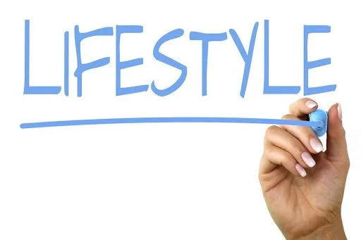 Hand holding a blue marker, writing the word 'LIFESTYLE' in blue above a horizontal line.