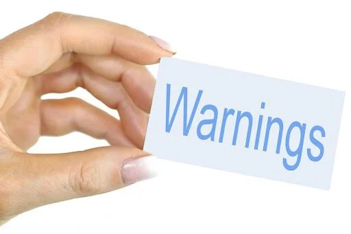 A hand holding a card that says 'Warnings' in blue text.