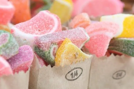 Close-up of colorful gummy candies with sugar coating in paper wrappers.