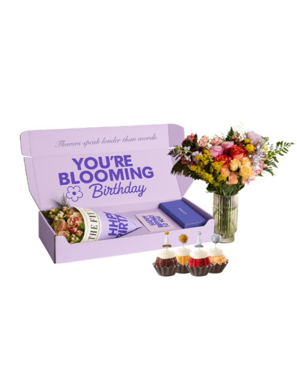 A birthday gift box with flowers, cupcakes, and a card that says "You're blooming birthday" and "Flowers speak louder than words."