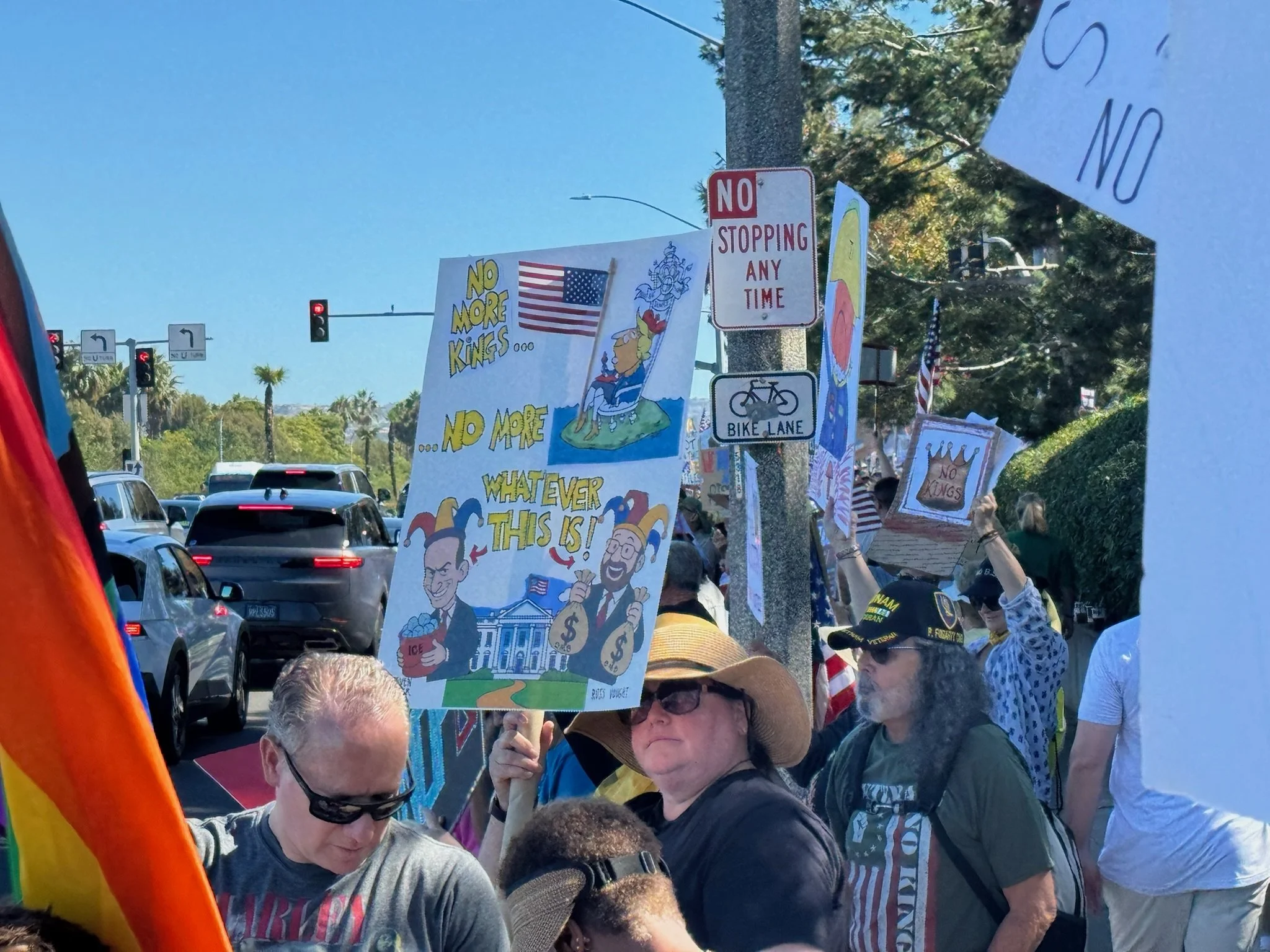 Crowd of protesters holding signs that oppose monarchy and support republican ideals, with traffic and traffic lights in the background.