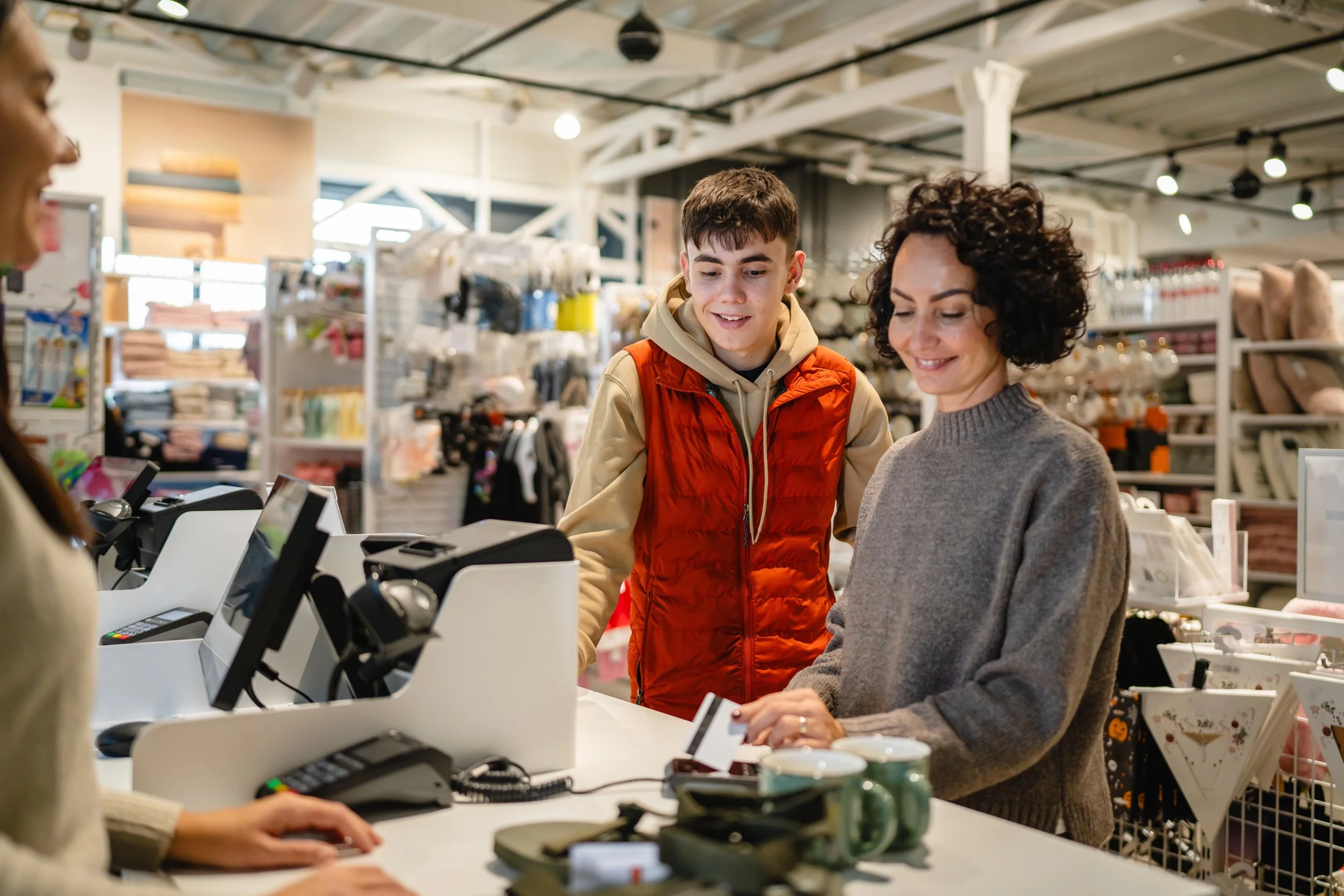 Customer and young man at retail checkout counter processing a sale using an integrated POS system in a home goods store