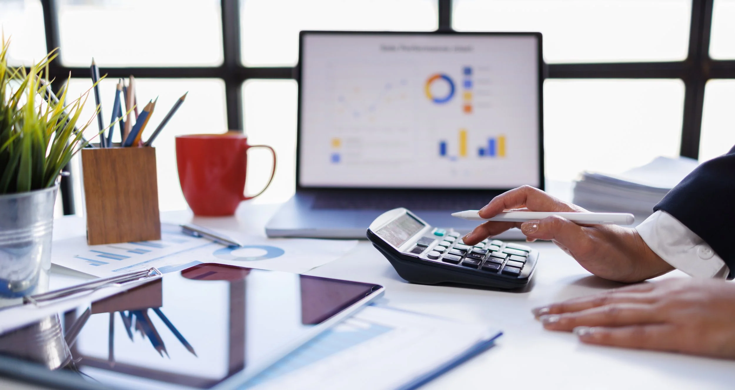 Retail manager reviewing sales data and reports on laptop with calculator, supporting retail business intelligence and analytics