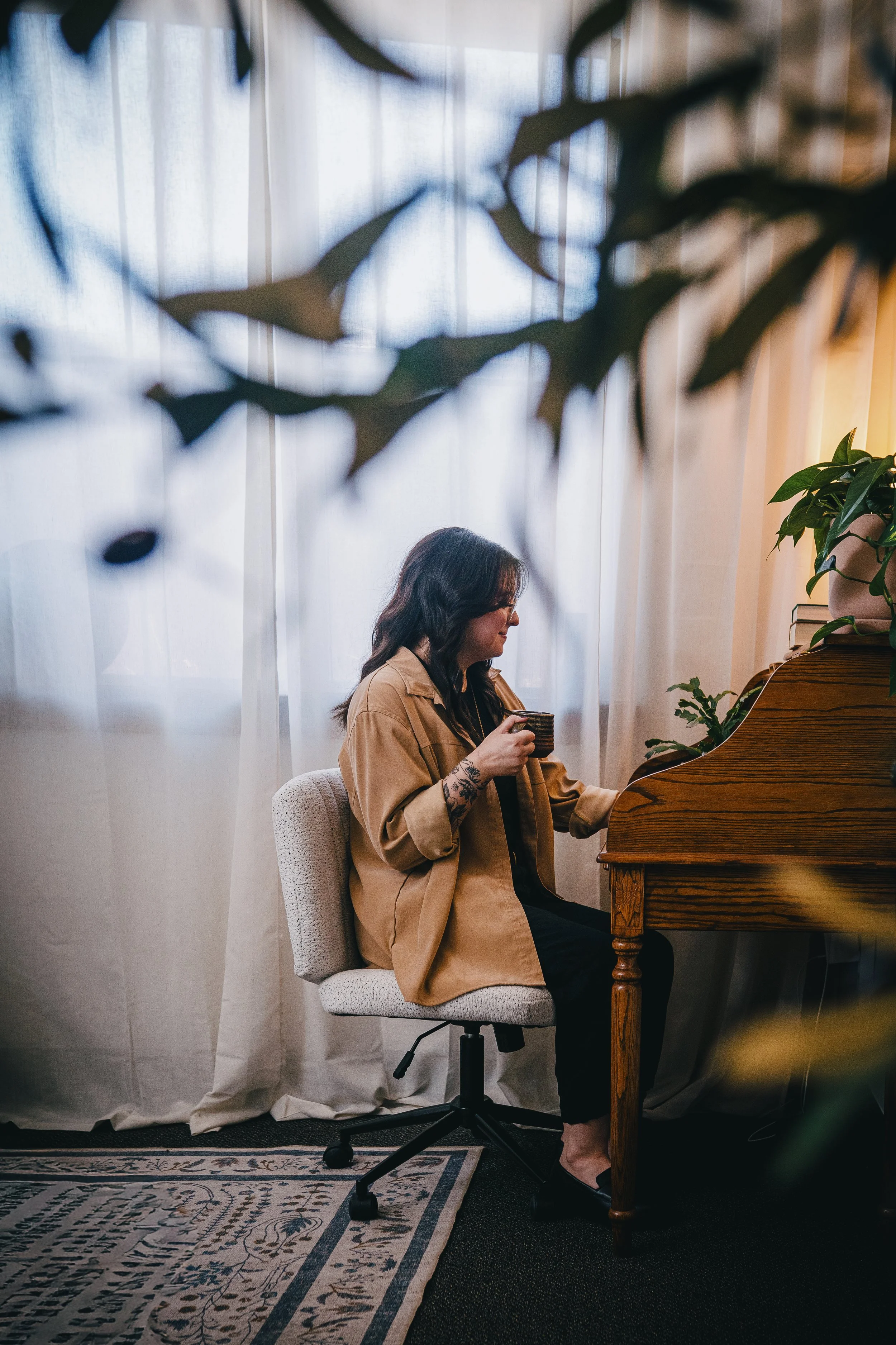 Joanna Jackson, LPC, sitting at her desk, holding a coffee mug and taking notes.