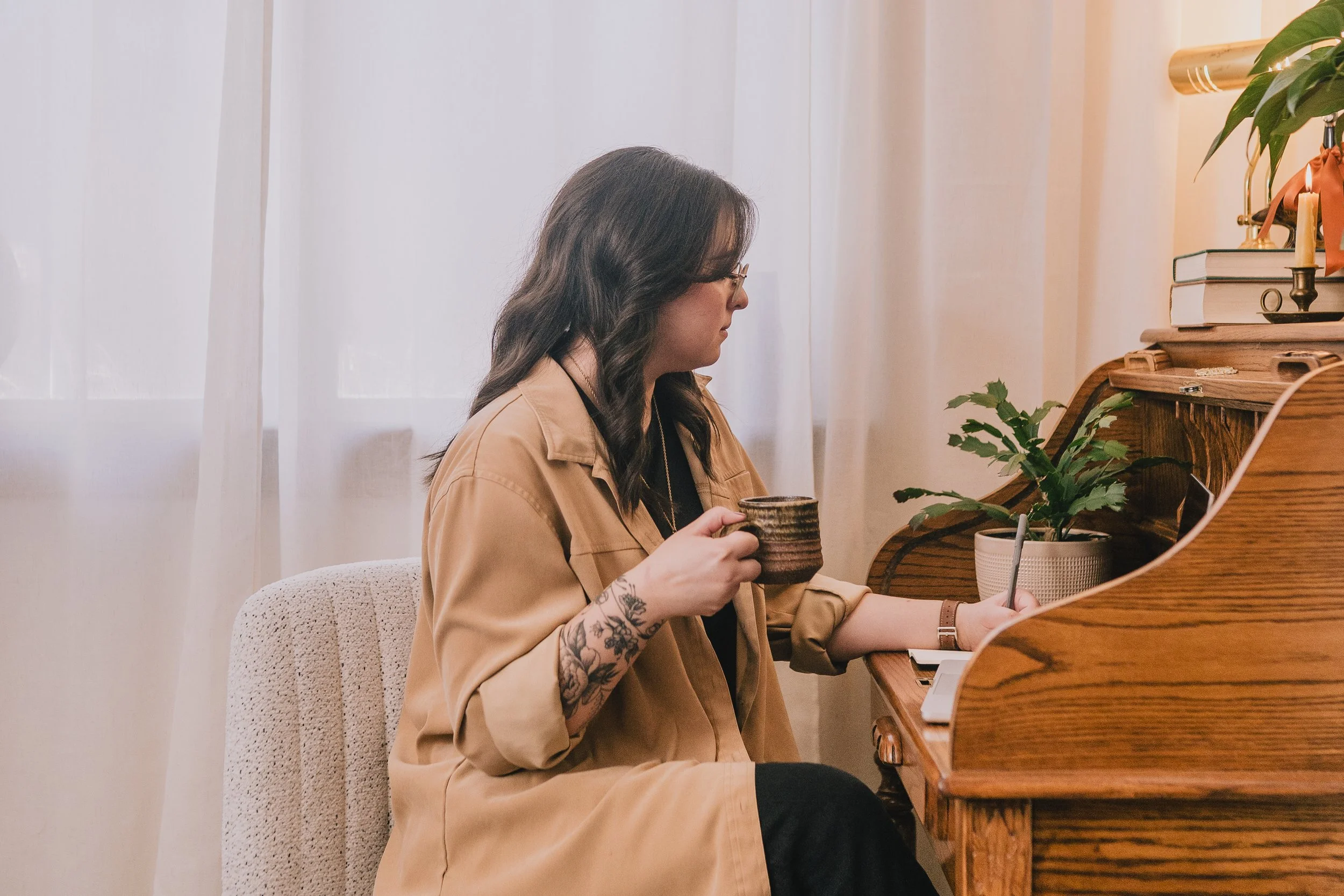 Joanna Jackson, LPC, sitting at a roll top desk, writing notes and holding a coffee mug.
