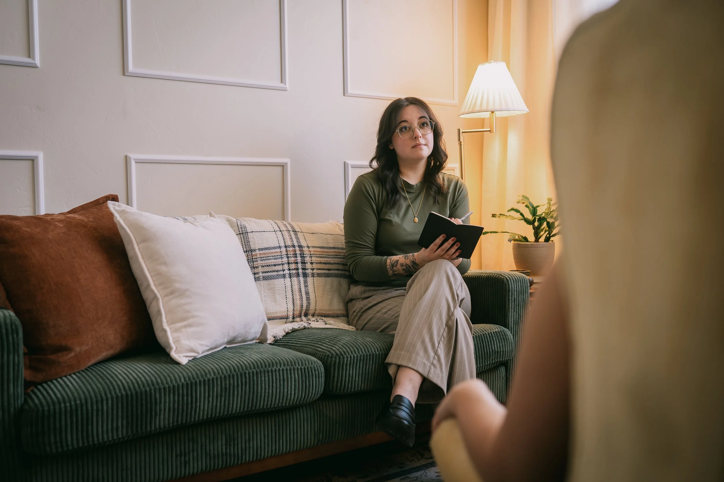 Joanna Jackson, LPC, sitting on a green couch, taking notes while engaging with a client.