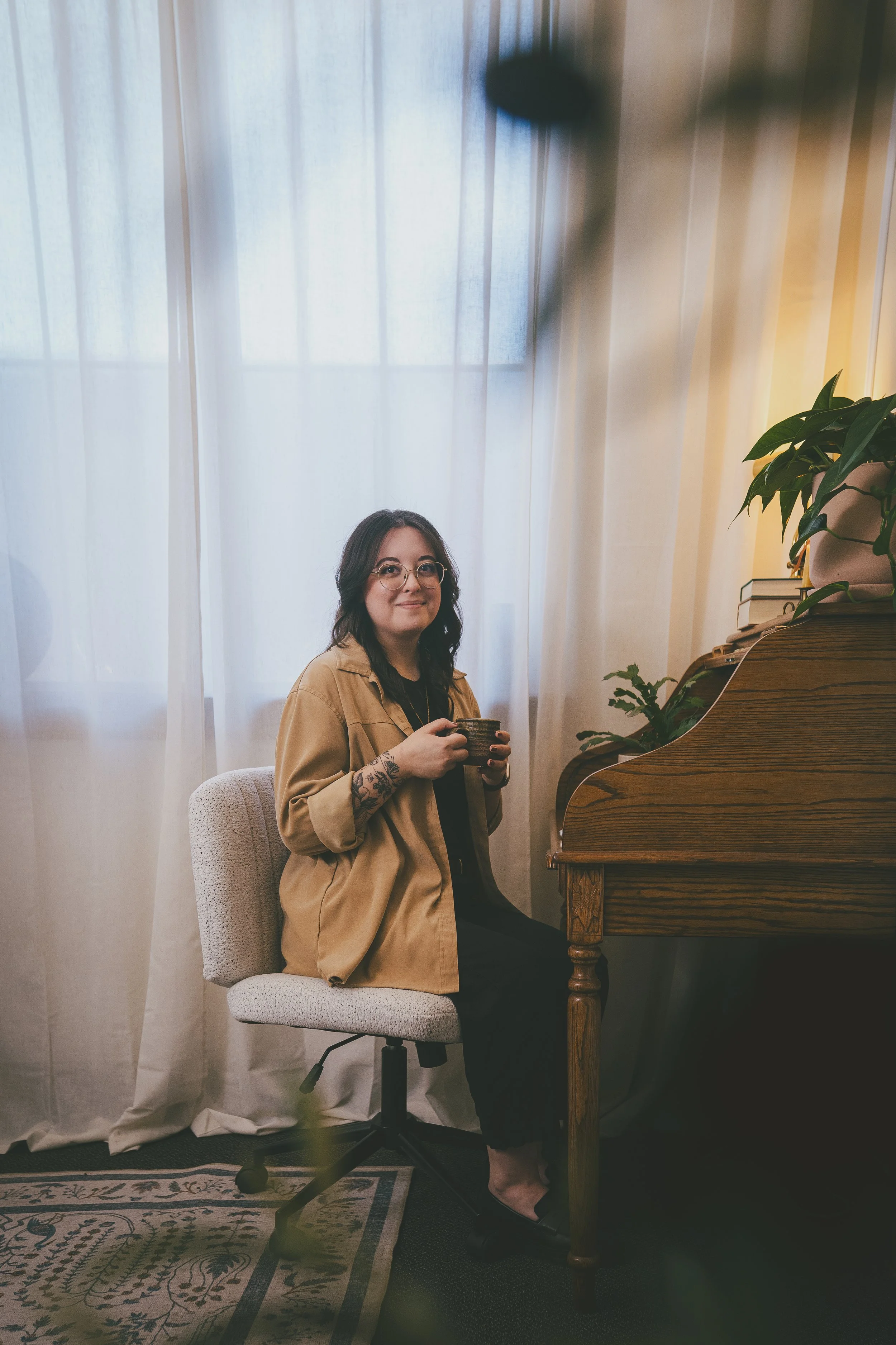 Joanna Jackson, LPC, sitting at her roll top desk while holding a coffee mug and smiling in greeting to you.