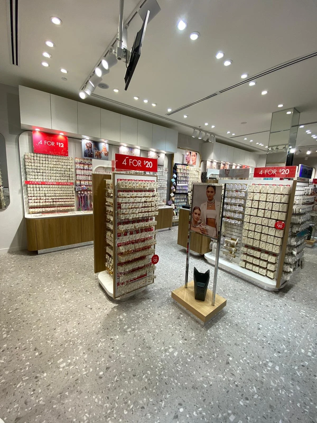 Jewelry display in a retail store, with various accessories on racks and red signs indicating promotions.