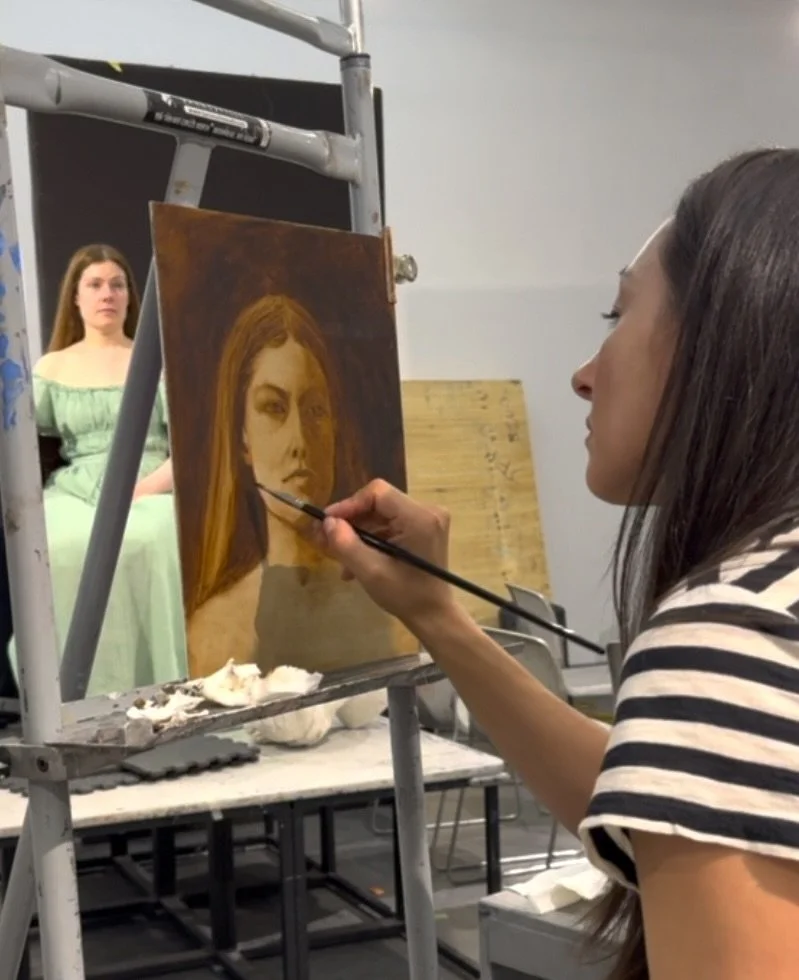 Artist working on a portrait of a woman in a green dress in an art studio. Copyright Eloise Parker.